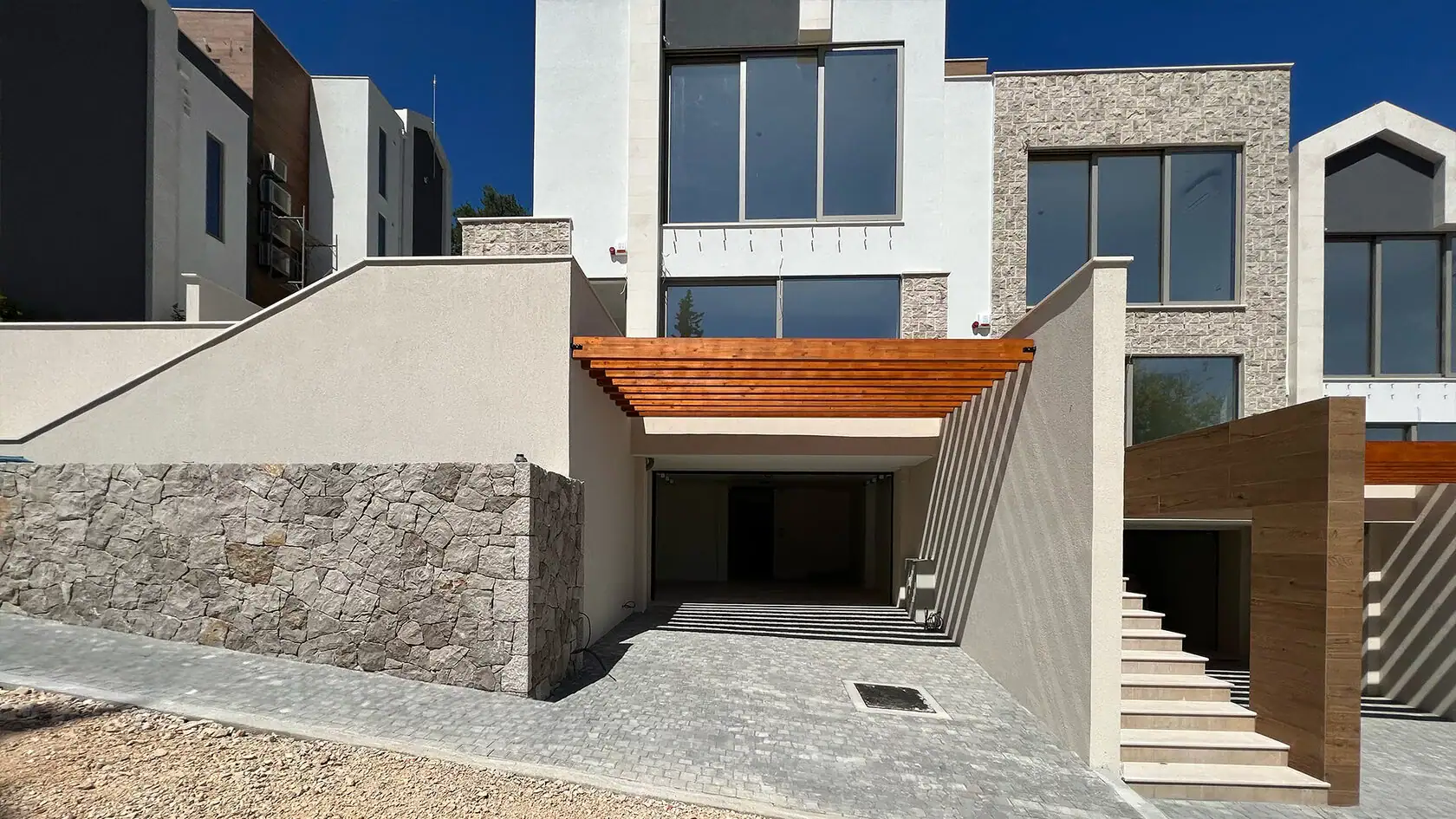 Moderne Villa in Tivat, Montenegro: Fassade mit Steinverkleidung, Panoramafenstern und überdachtem Stellplatz.