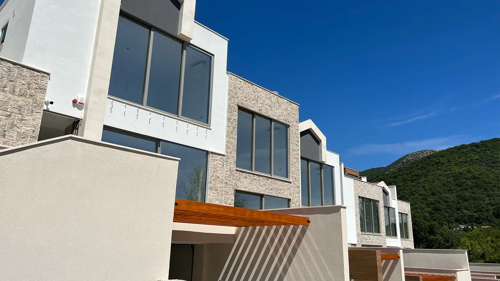 Moderne Stadthäuser mit Panoramafenstern und Steinverkleidung der Fassade in Tivat, Montenegro.