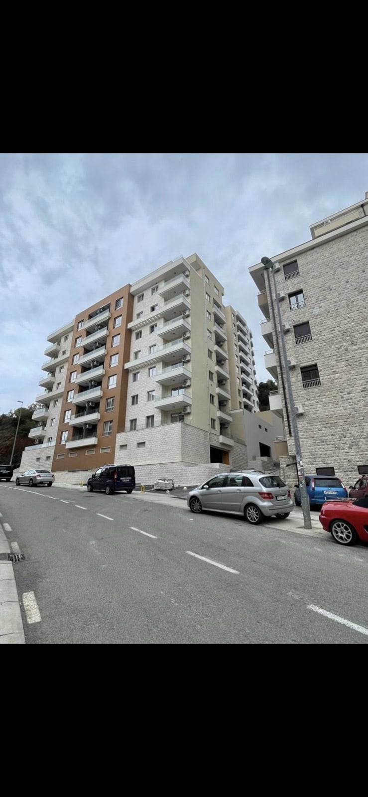 Savremena višespratna stambena zgrada s balkonima u Bečićima, Crna Gora, pogled na fasadu zgrade sa ulice.