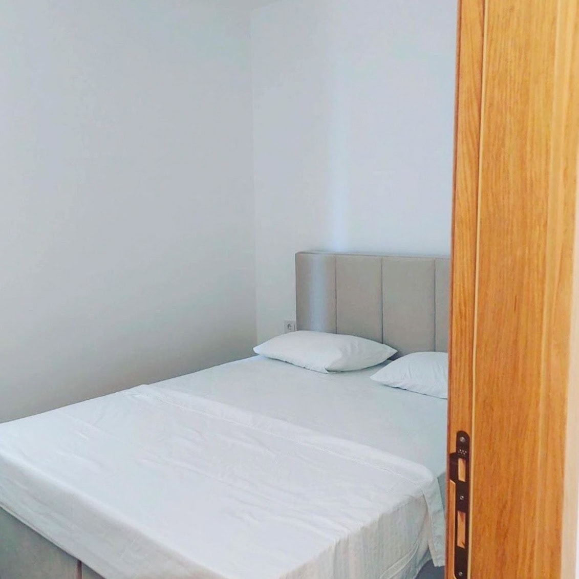 Svetla spavaća soba sa bračnim krevetom u stanu u Bečićima, Crna Gora, moderan enterijer sa belim zidovima.