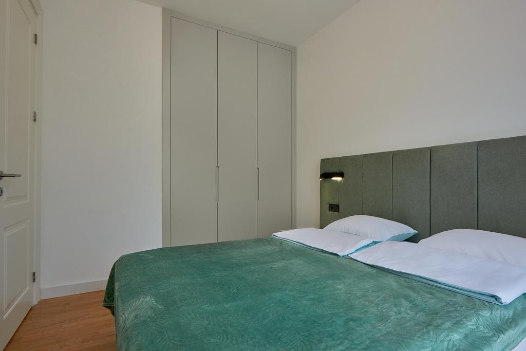 Nowoczesna sypialnia z łóżkiem dwuosobowym i wbudowaną szafą w apartamencie, Bečići, Czarnogóra.