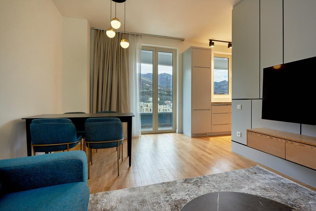 Nowoczesny salon w mieszkaniu w Bečići, Czarnogóra: stylowe meble, parkiet, widok na góry i wyjście na balkon.