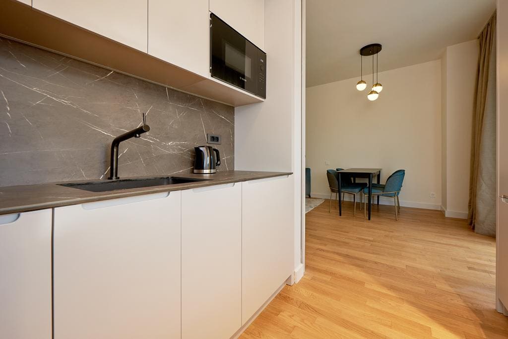 Nowoczesna кухня z marmurowym panelem nad blatem i jadalnia w apartamencie, Bečići, Czarnogóra.
