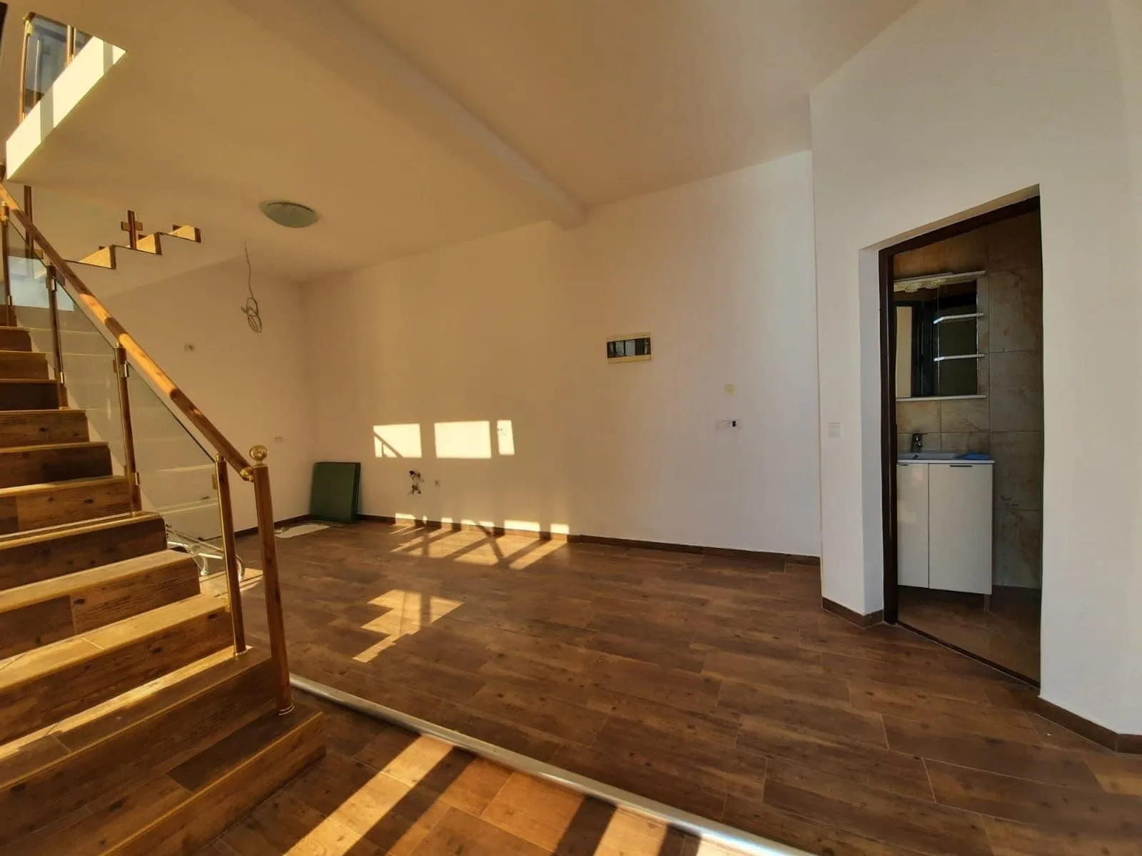 Salon avec escalier en bois et finitions lumineuses dans une villa à Dobra Voda, Monténégro. Vue sur l'intérieur avec salle de bain.