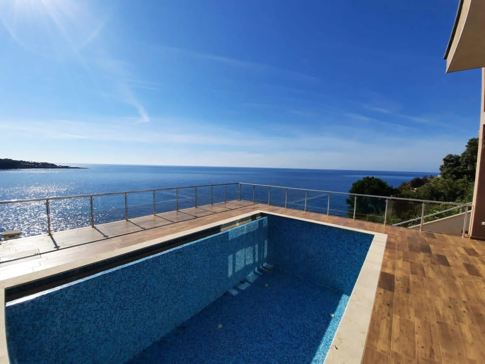 Piscine extérieure sur la terrasse d'une villa à Dobra Voda, Monténégro, avec vue panoramique sur la mer Adriatique et les montagnes.