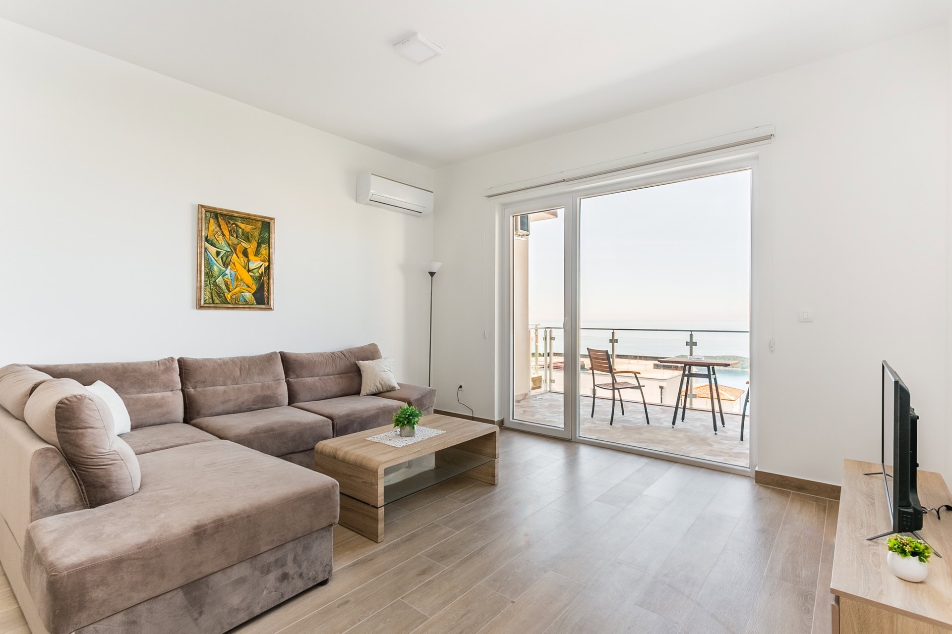 Salon avec canapé d’angle et accès à la terrasse avec vue sur la mer dans un appartement, Seoce, Budva, Monténégro.