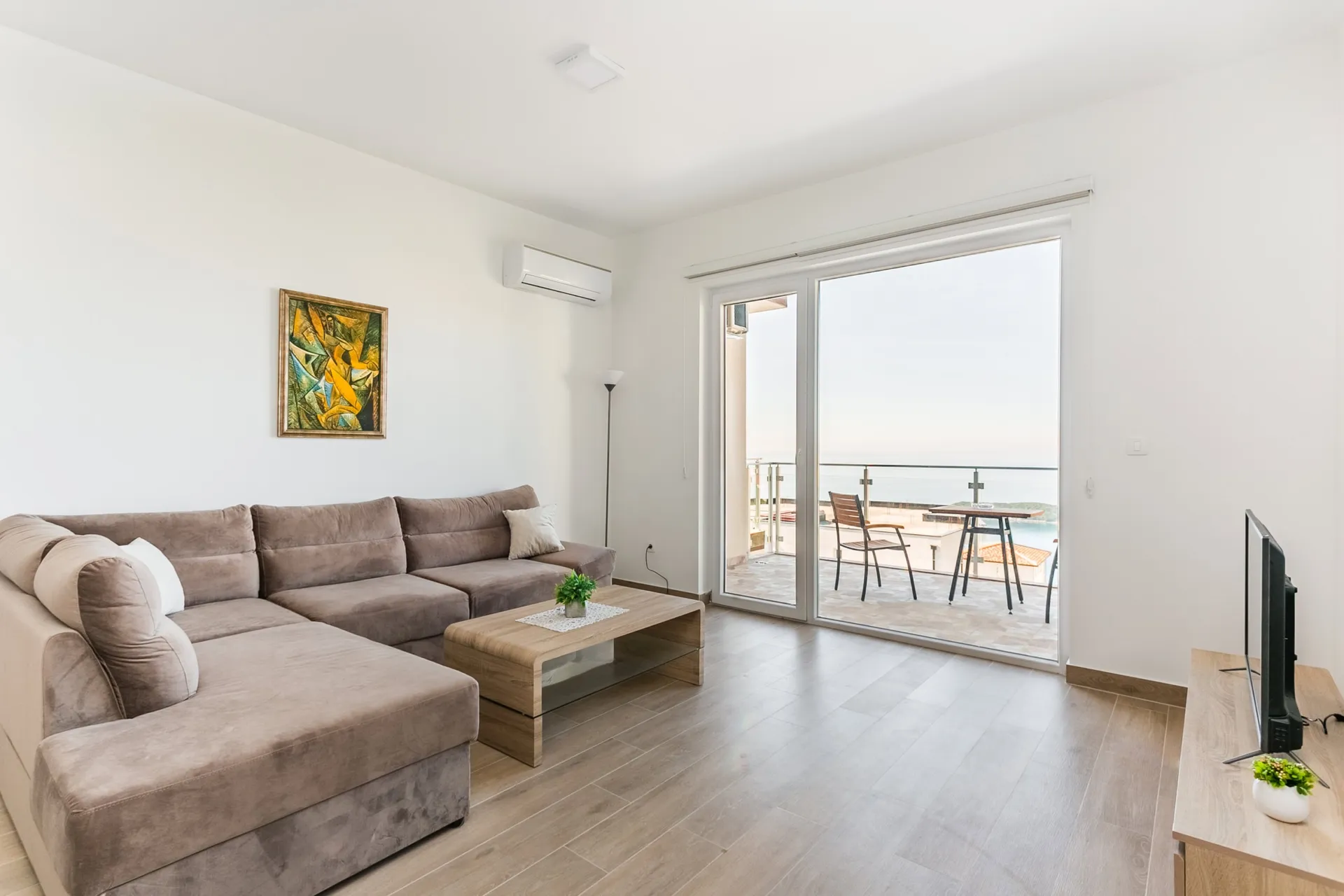 Helles Wohnzimmer mit Ecksofa und Terrasse mit Meerblick in einer Wohnung, Seoce, Budva, Montenegro.