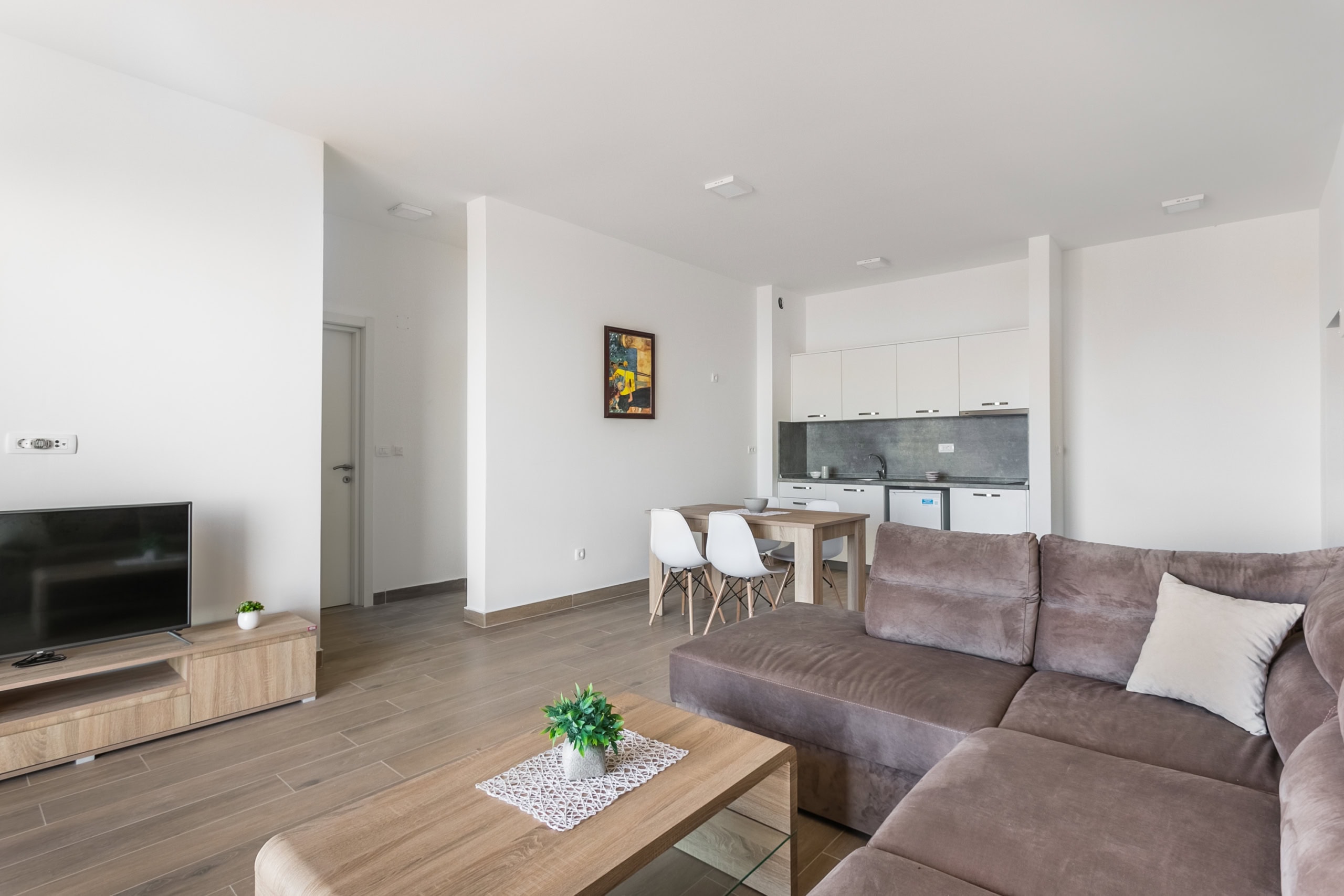 Salon moderne avec cuisine dans un appartement, Seoce, Budva, Monténégro : canapé marron, coin repas et intérieur lumineux.