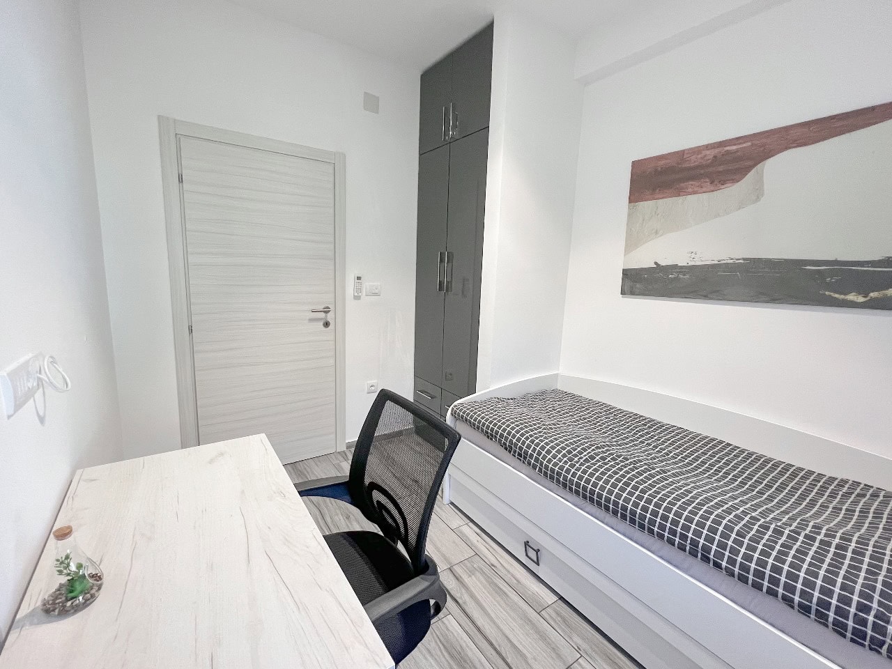 Modernes Schlafzimmer mit Arbeitsbereich in einer Wohnung, Tivat, Montenegro: Bett, Schreibtisch und Einbauschrank.