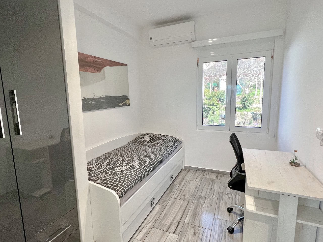 Helles Schlafzimmer mit Einzelbett, Schreibtisch und Kleiderschrank in einer Wohnung, Stadt Tivat, Montenegro.