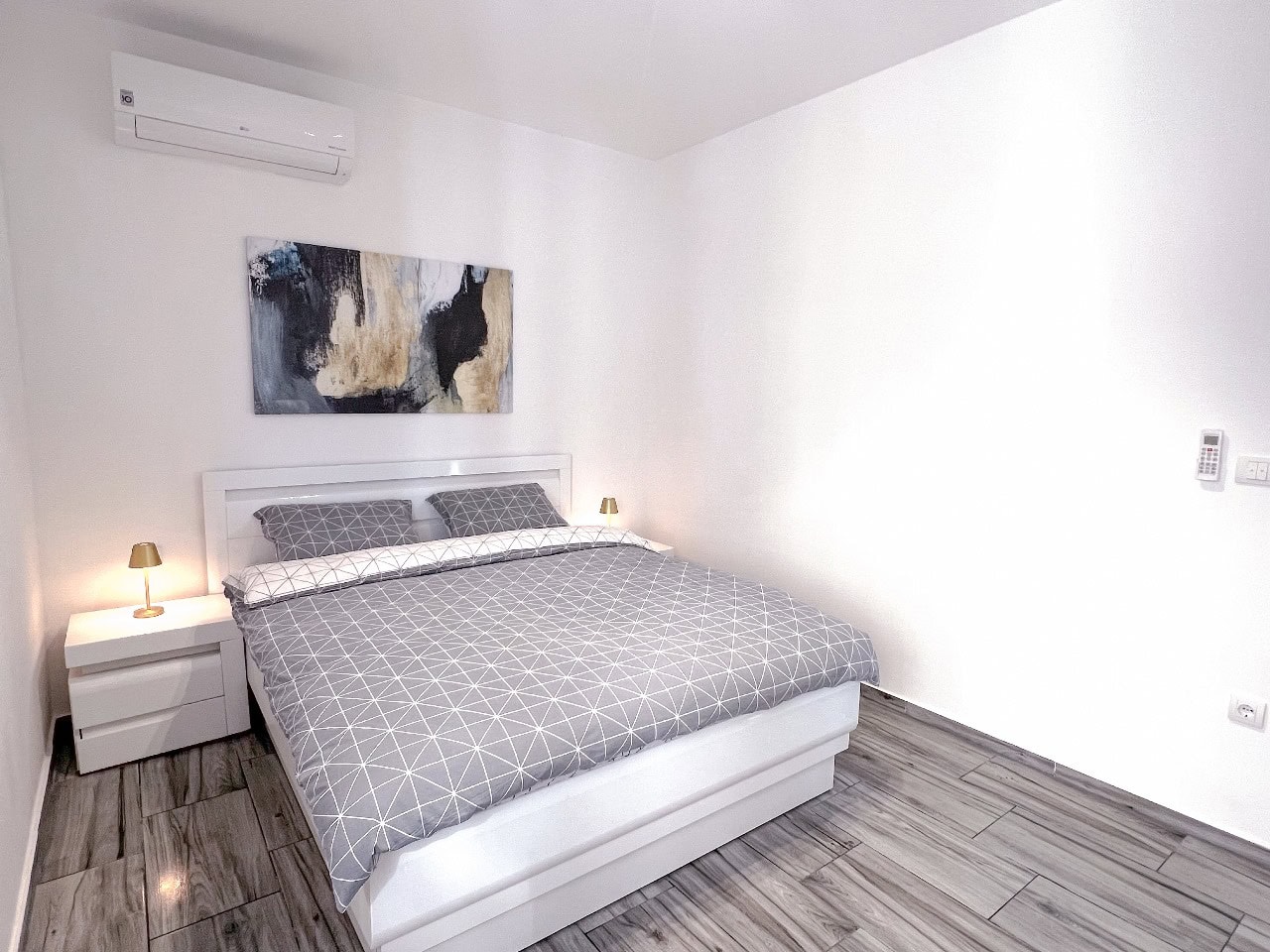Modernes Schlafzimmer mit Doppelbett in einer Wohnung in Tivat, Montenegro: helles Interieur, Klimaanlage und Fliesen.