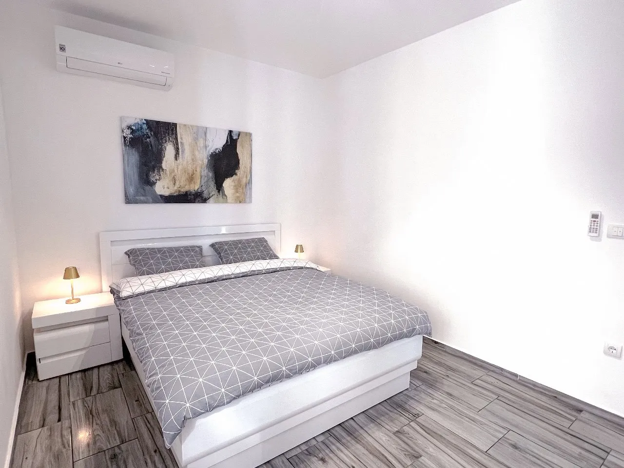Modernes Schlafzimmer mit Doppelbett in einer Wohnung in Tivat, Montenegro: helles Interieur, Klimaanlage und Fliesen.