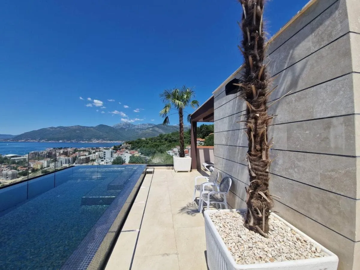 Terrasse mit Infinity-Pool und Meerblick in Tivat, Montenegro: moderne Steinverkleidung und Palmen.