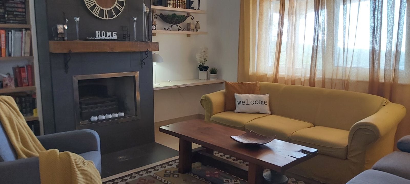 Şömineli ve yumuşak mobilyalı уютная oturma odası, Kırımovitsa, Karadağ. Kitap rafları ve dekorlu iç mekan.