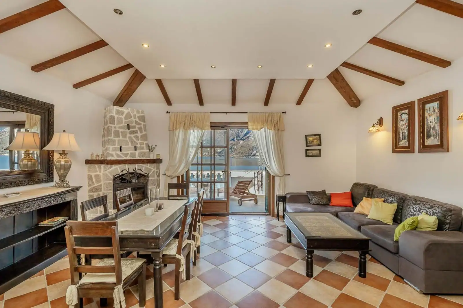 Living room with a fireplace, wooden beams, and sea view in an apartment in Kostanica, Montenegro.