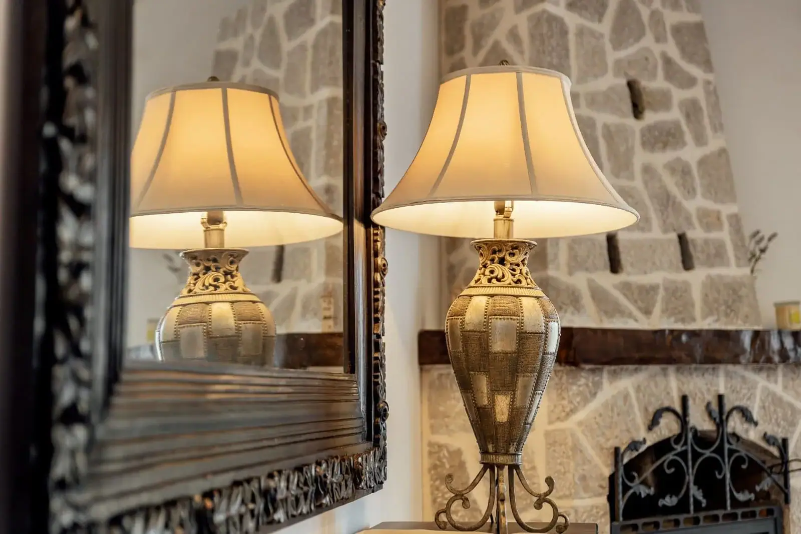 Vintage table lamp and mirror in the living room of an apartment in Kostanica, Montenegro, against a stone fireplace.