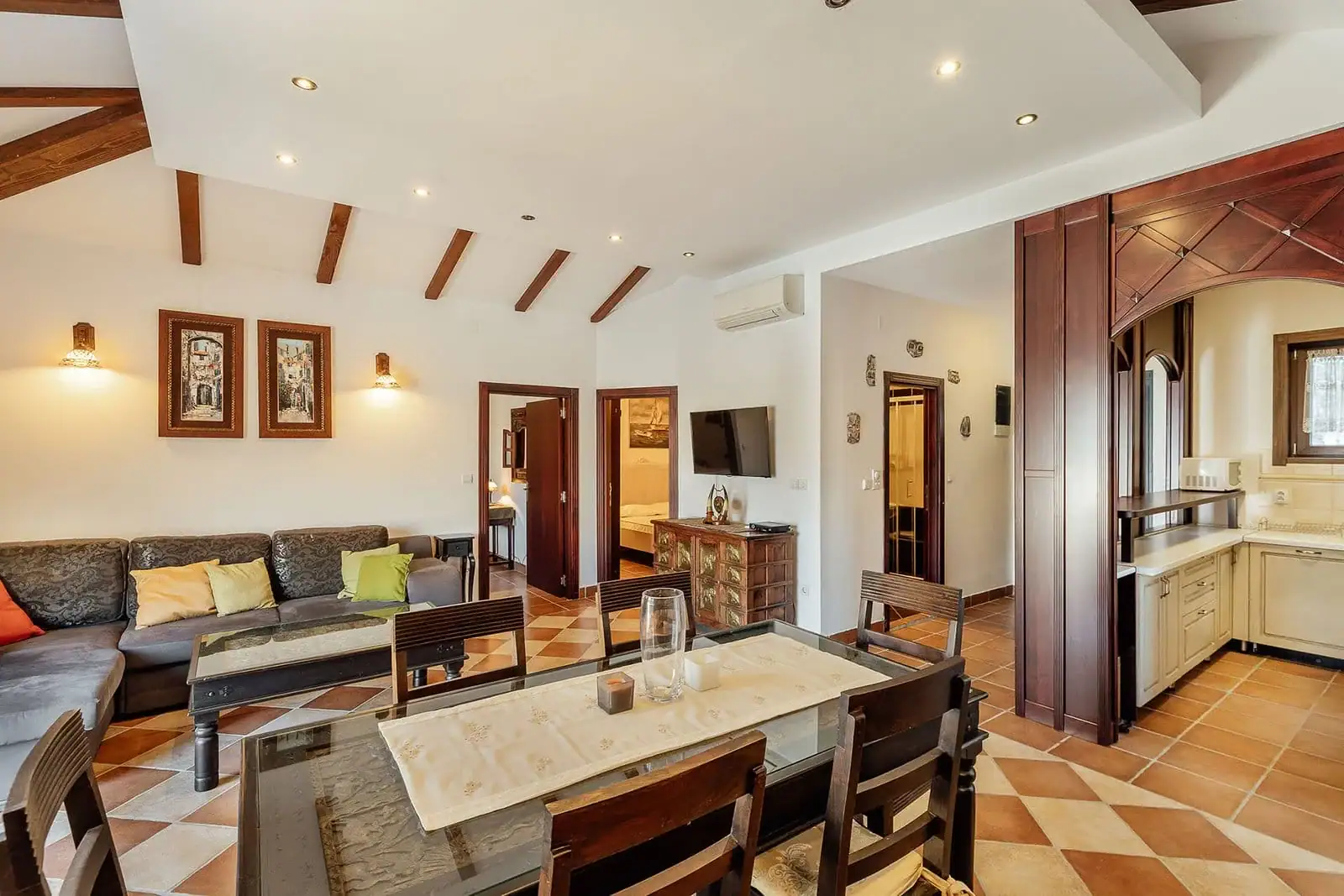Living room with dining area in an apartment, Kostanica, Montenegro: wooden beams, tiled floor, and classic furniture.