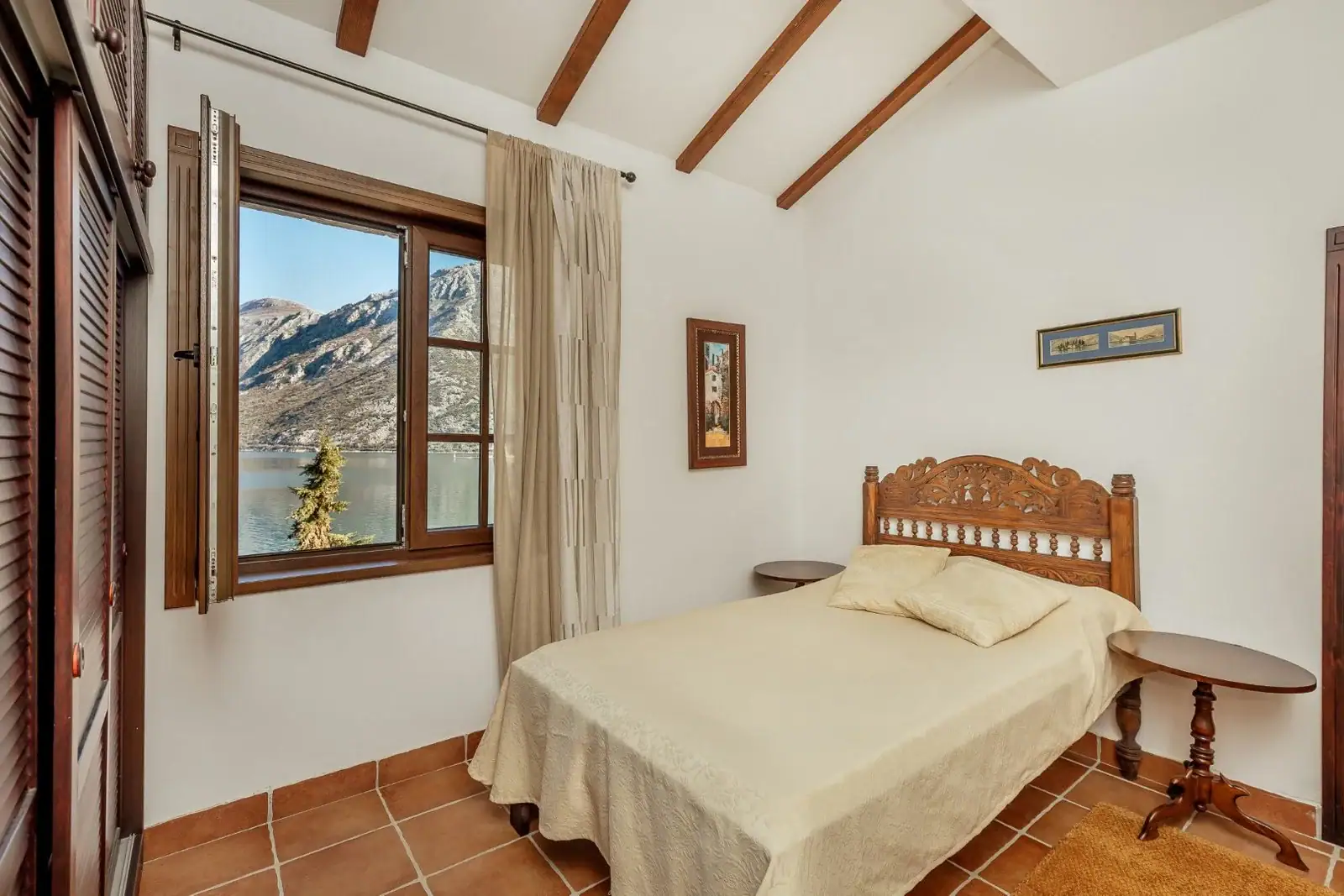 Bedroom with a view of Kotor Bay in an apartment, Kostanjica, Montenegro: double bed, wooden beams, tile flooring.