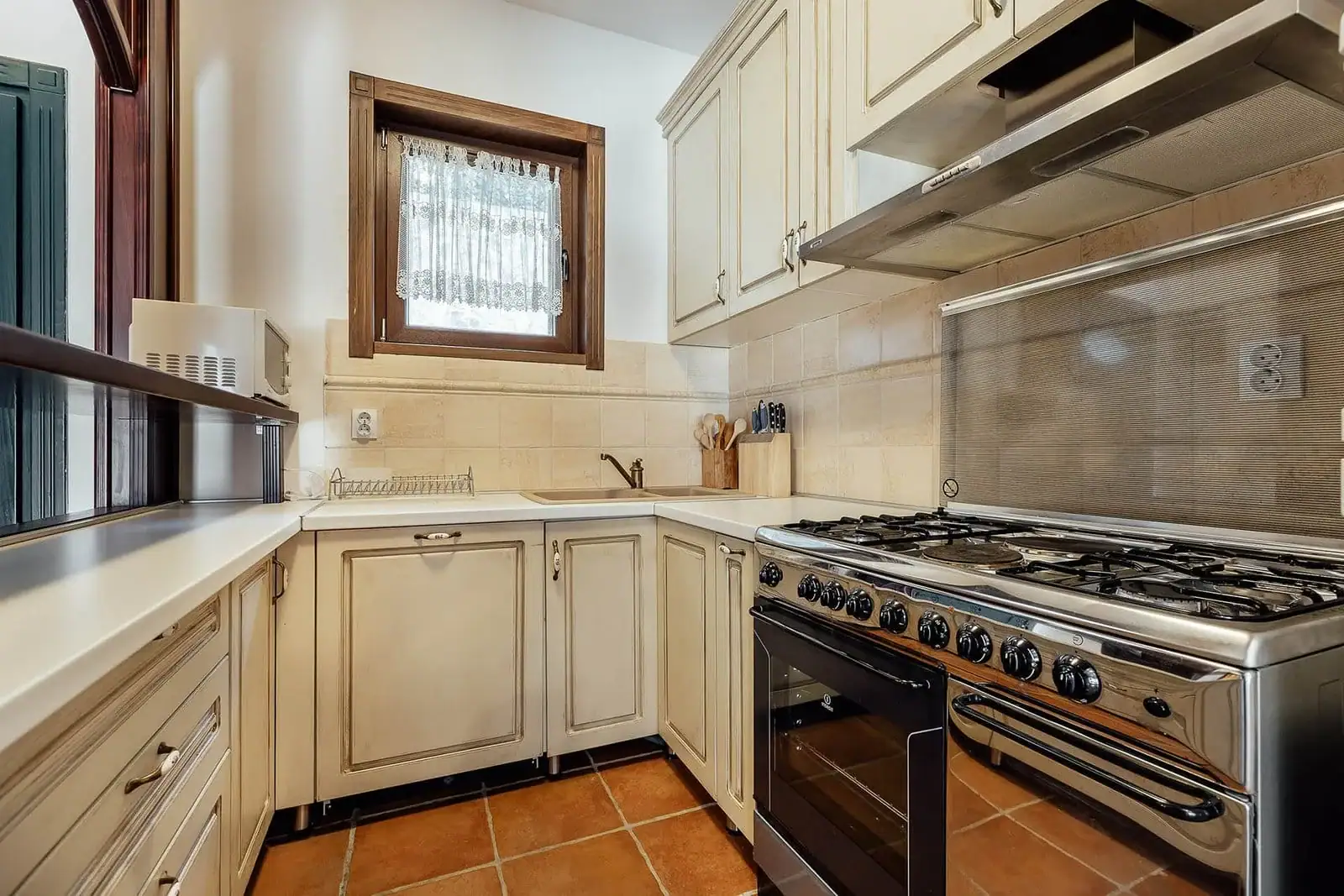 Cozy classic-style kitchen in an apartment, Kostanica, Montenegro: light cabinetry, gas stove, and tiled floor.
