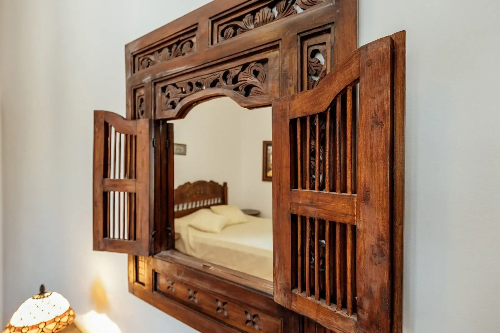 Decorative wooden mirror with shutters in the bedroom of an apartment in Kostanica, Montenegro.