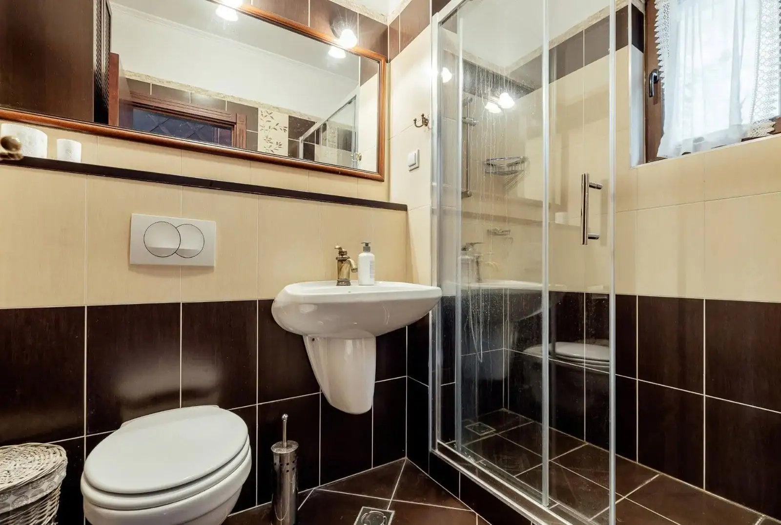 Bathroom in an apartment in Kostanica, Montenegro: shower cabin, brown tile, and a mirror in a wooden frame.