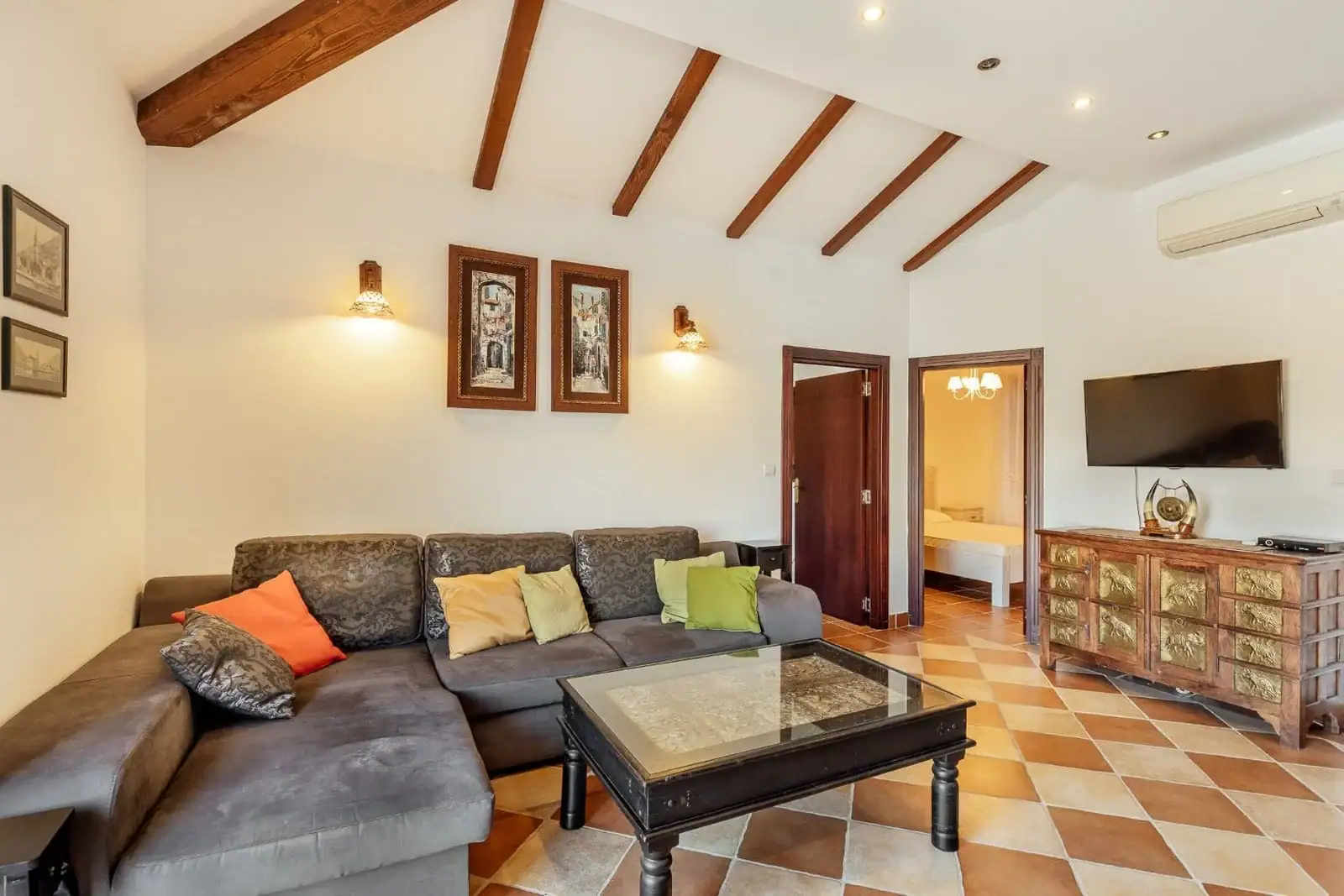 Living room in an apartment in Kostanica, Montenegro: gray sofa, wooden ceiling beams, and tiled floor.