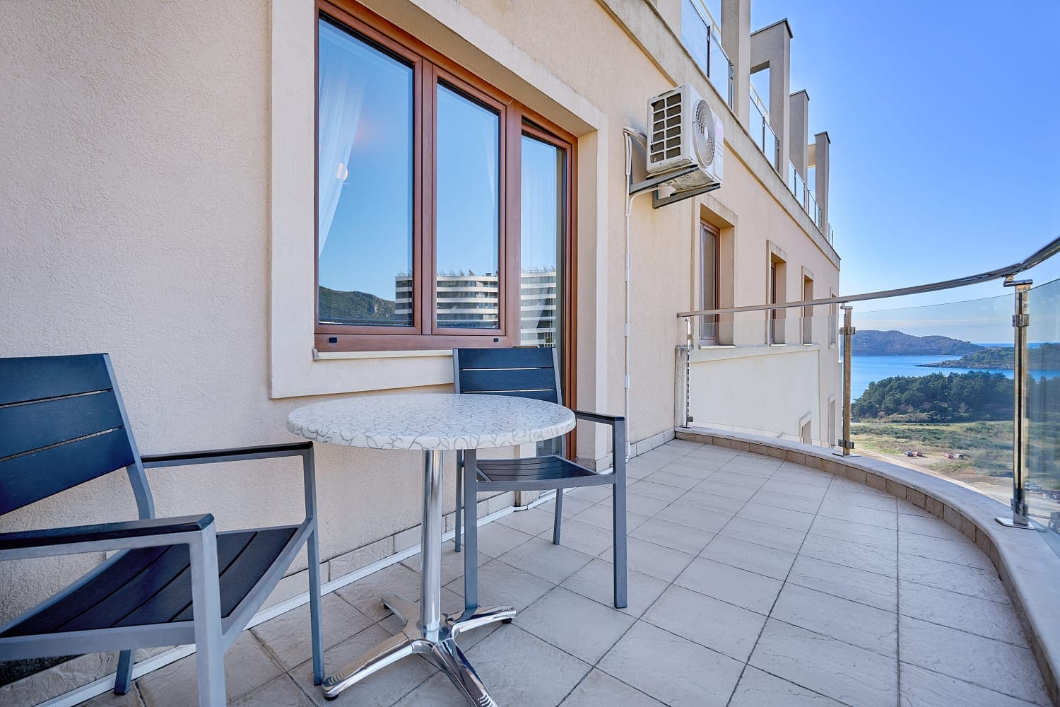 Balkon apartmana u Bečićima, Crna Gora: sto sa stolicama, panoramski pogled na more i planine, moderna završna obrada.
