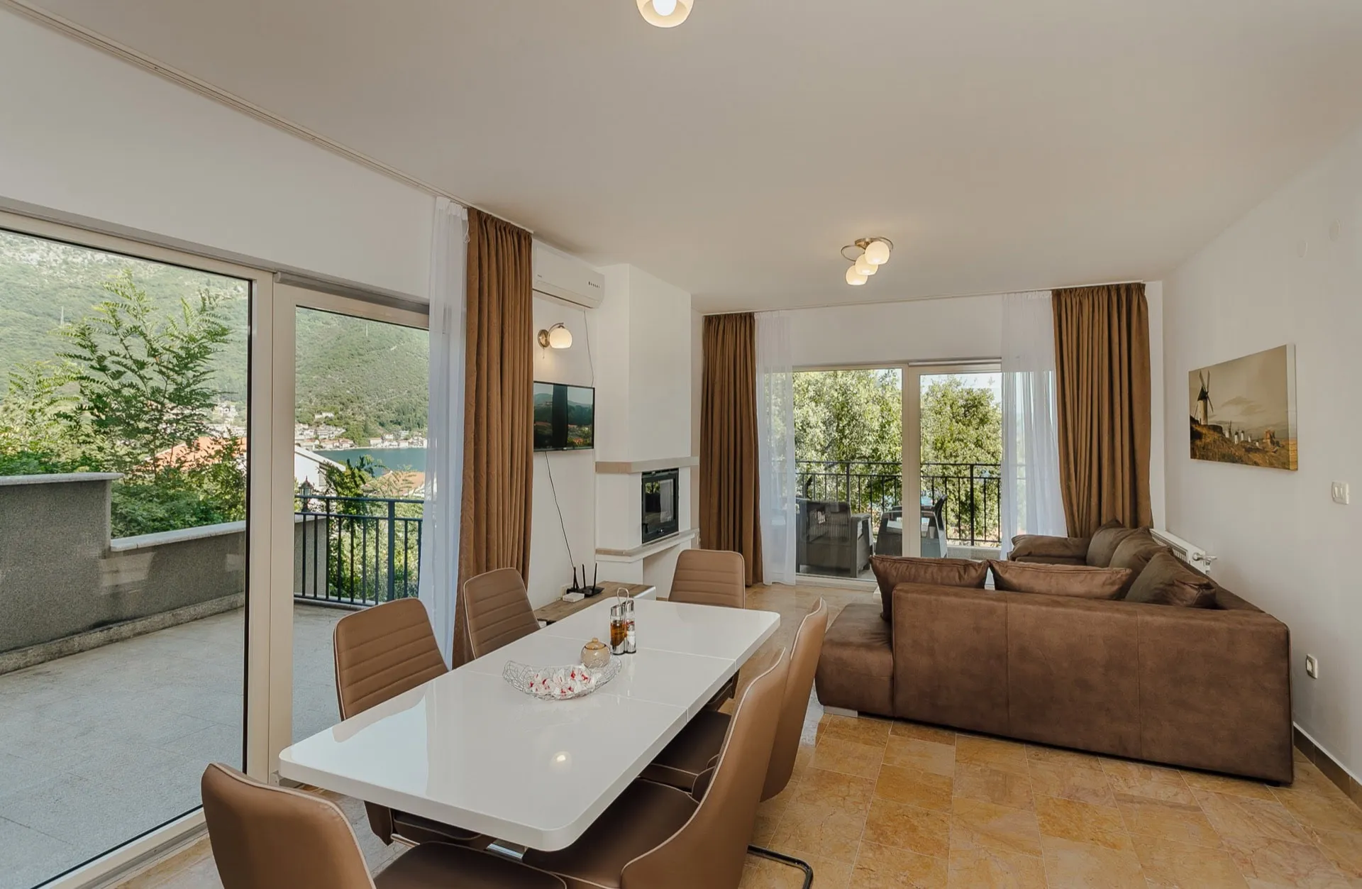 Salon avec coin repas et vue panoramique sur la mer dans un appartement à Kamenari, Monténégro. Mobilier moderne et terrasse.