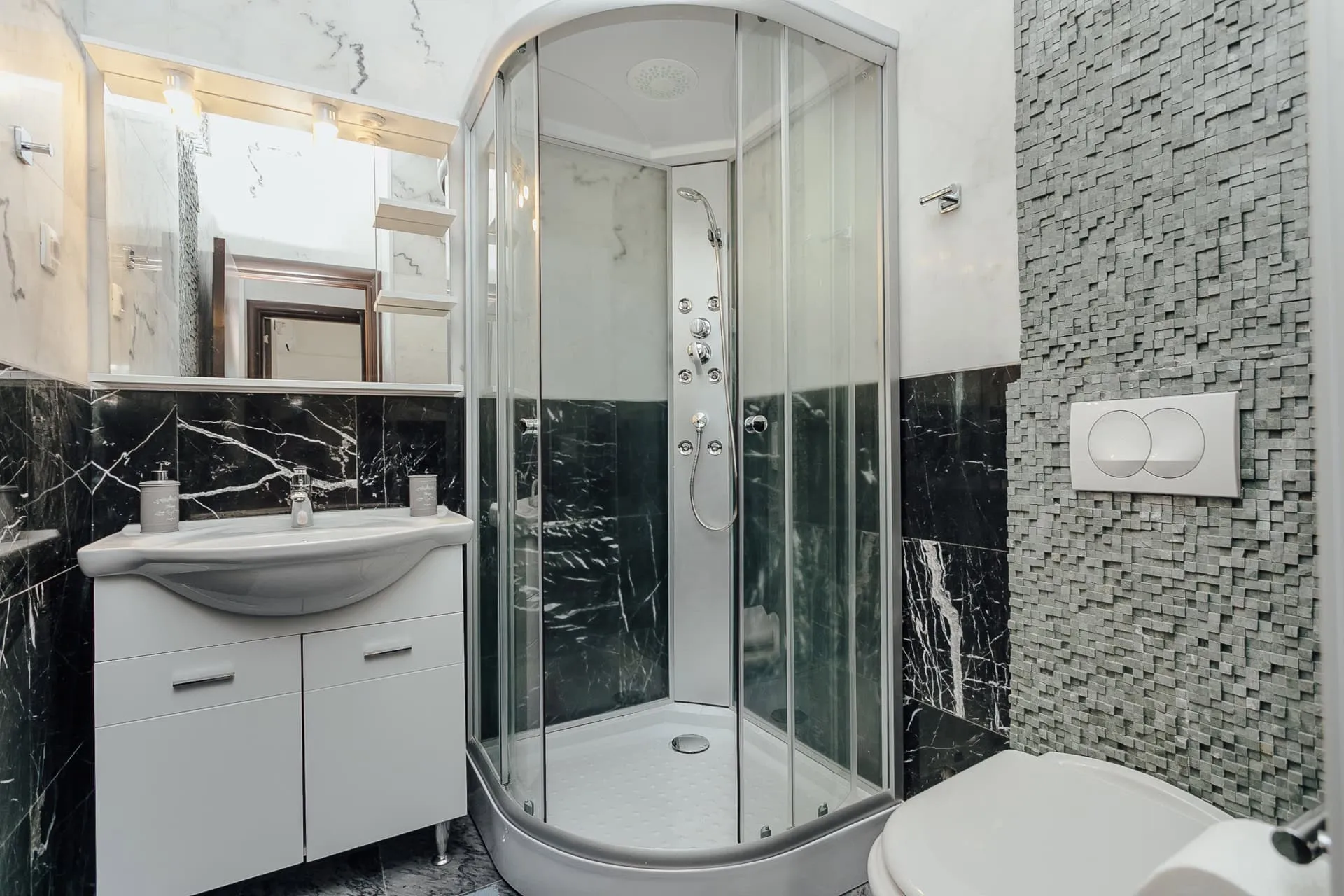 Salle de bains moderne avec cabine de douche et finitions en marbre noir dans un appartement, Kamenari, Monténégro.