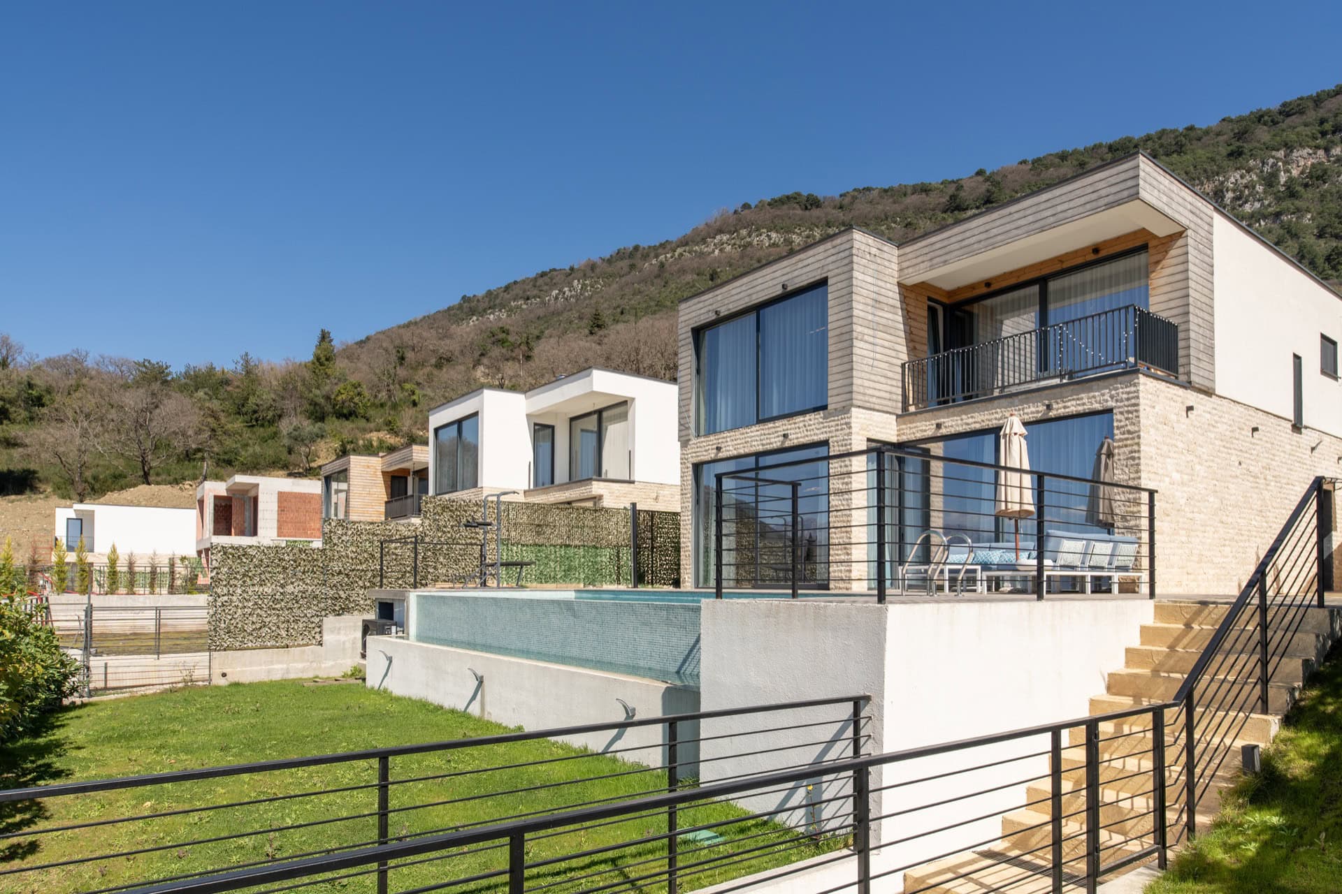 Modern villas with panoramic windows, terraces, and pools in Kavac, Montenegro: view of an upscale residential complex.