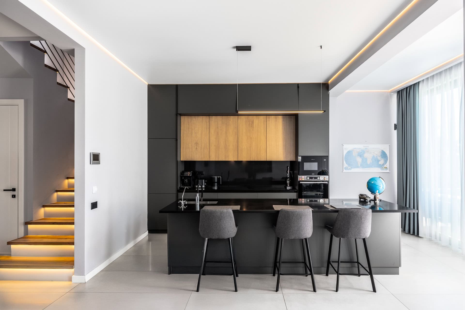 Modern kitchen with an island and staircase lighting in a villa in Kavac, Montenegro. Minimalist-style interior.