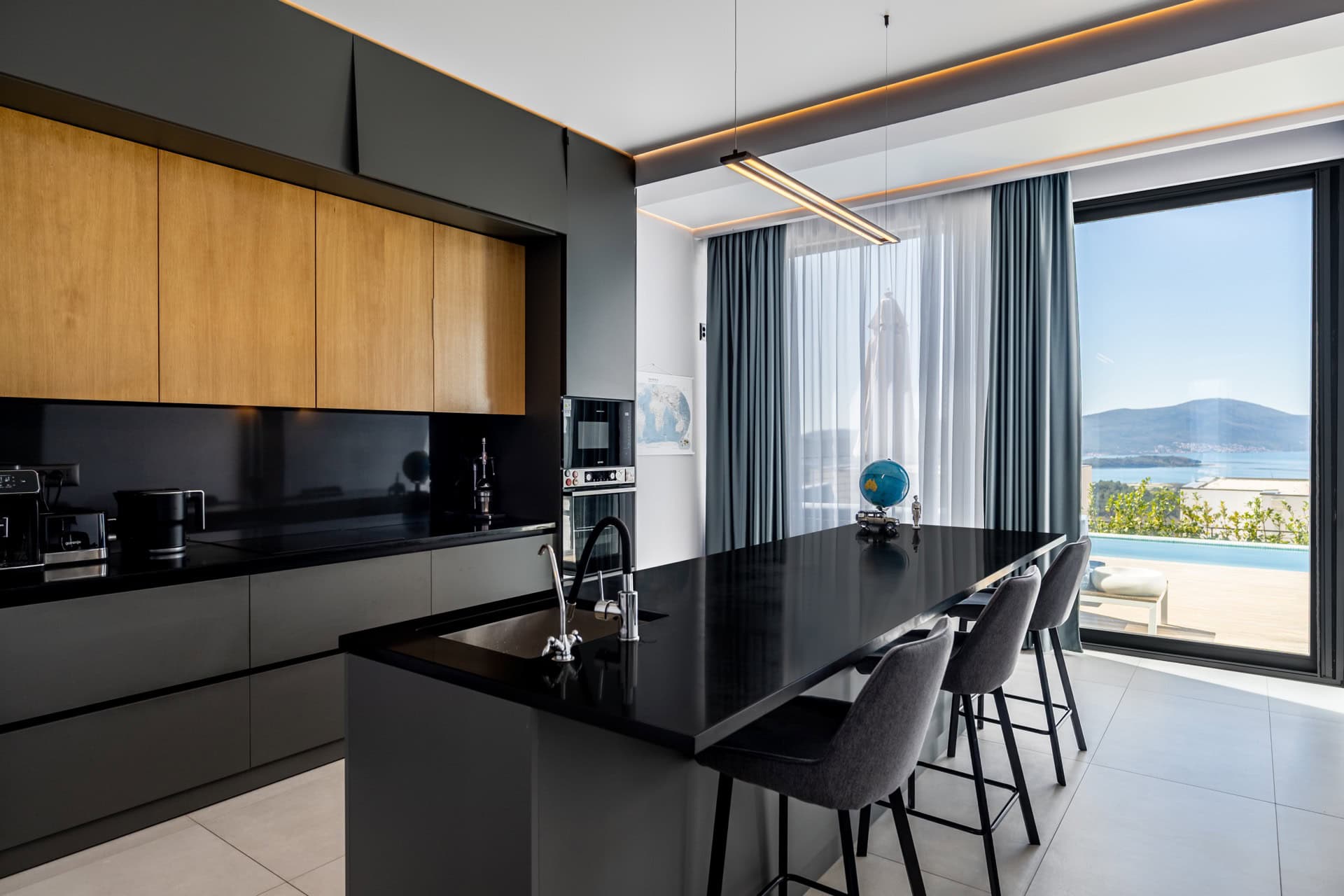 Modern kitchen with an island in a villa in Kavac, Montenegro, with panoramic sea and pool views.