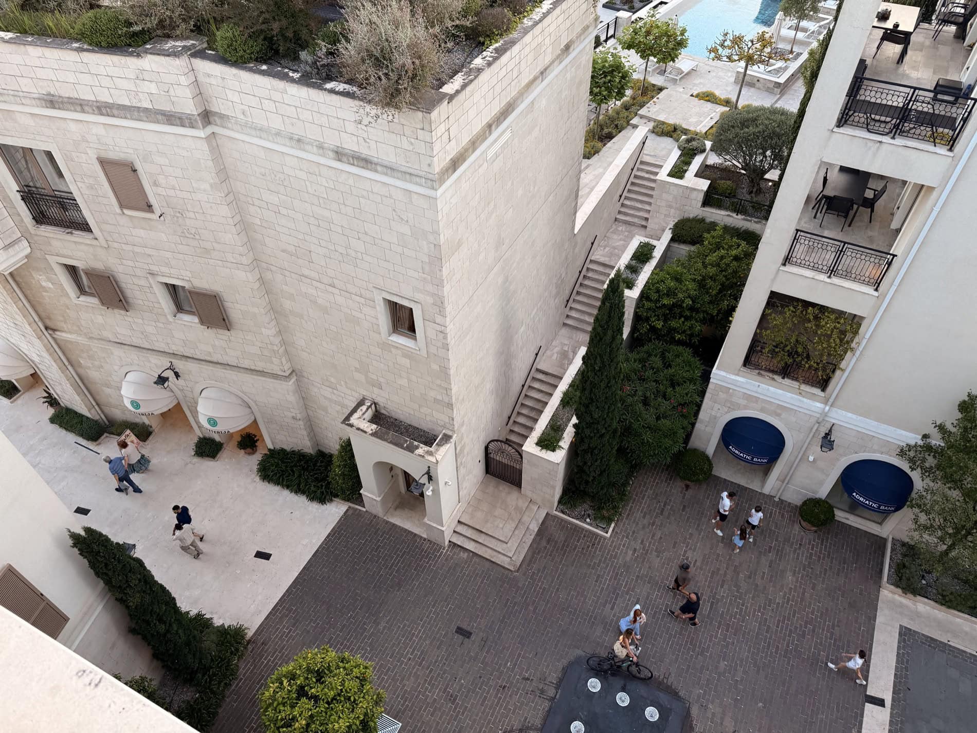 Вид сверху на жилой комплекс Porto Montenegro в Тивате, Черногория: каменные фасады, пешеходная площадь и бассейн.
