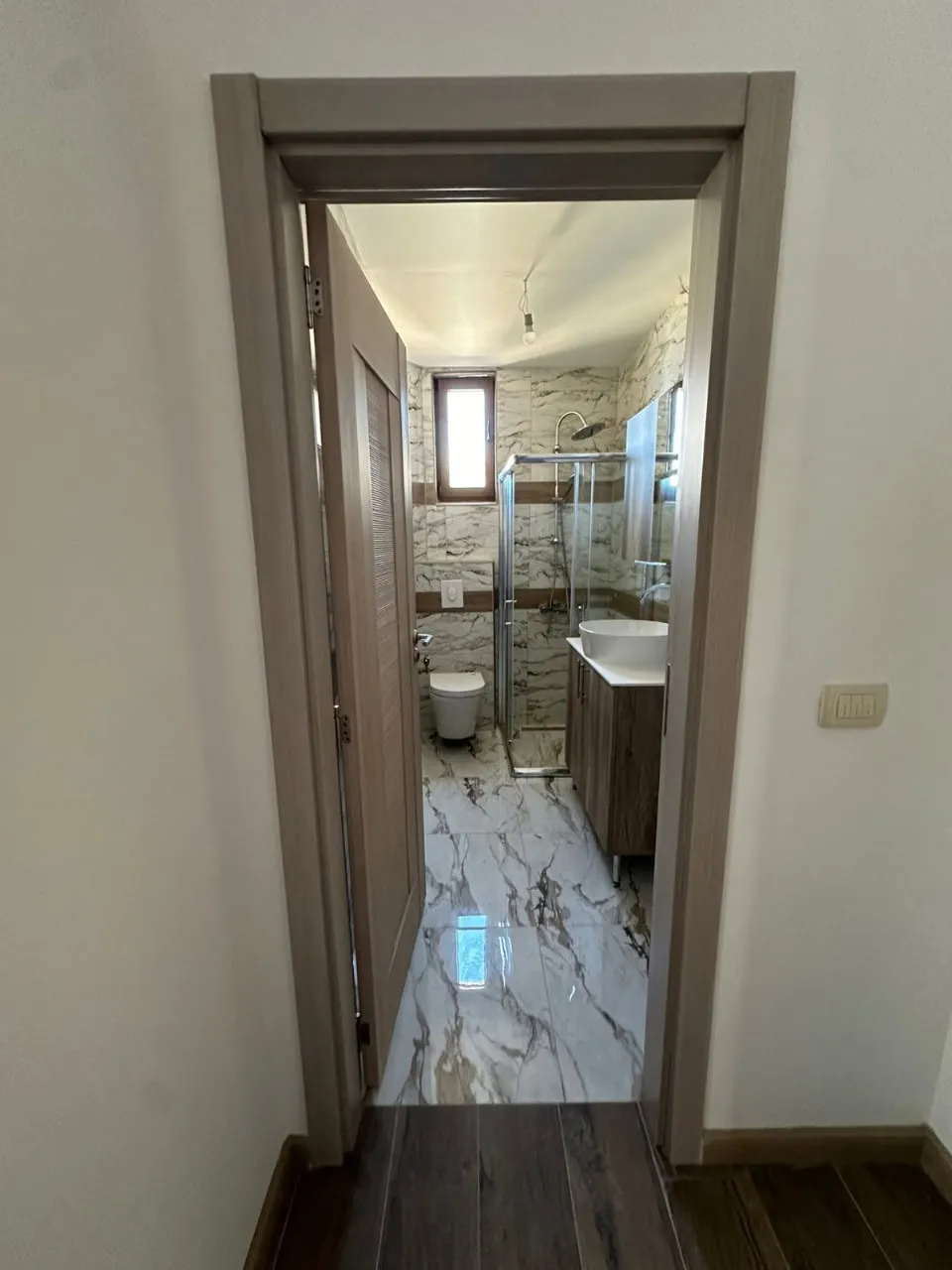 Blick auf ein kleines modernes Badezimmer durch eine offene Tür
