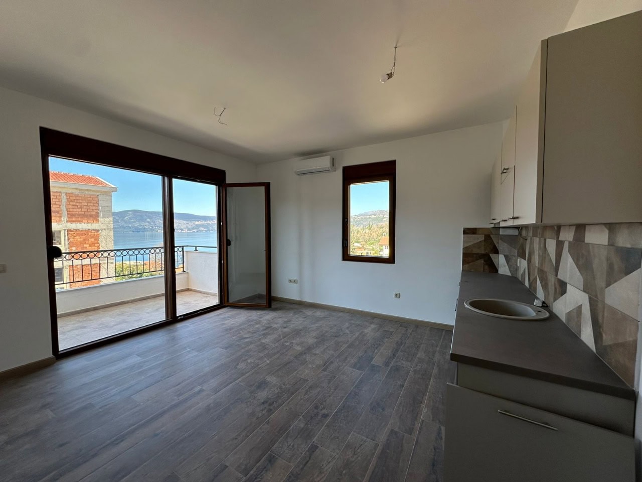 Küche-Wohnzimmer mit Zugang zur Terrasse und Meerblick in einer Wohnung in Kumbor, Montenegro: moderne Ausstattung und Möbel.