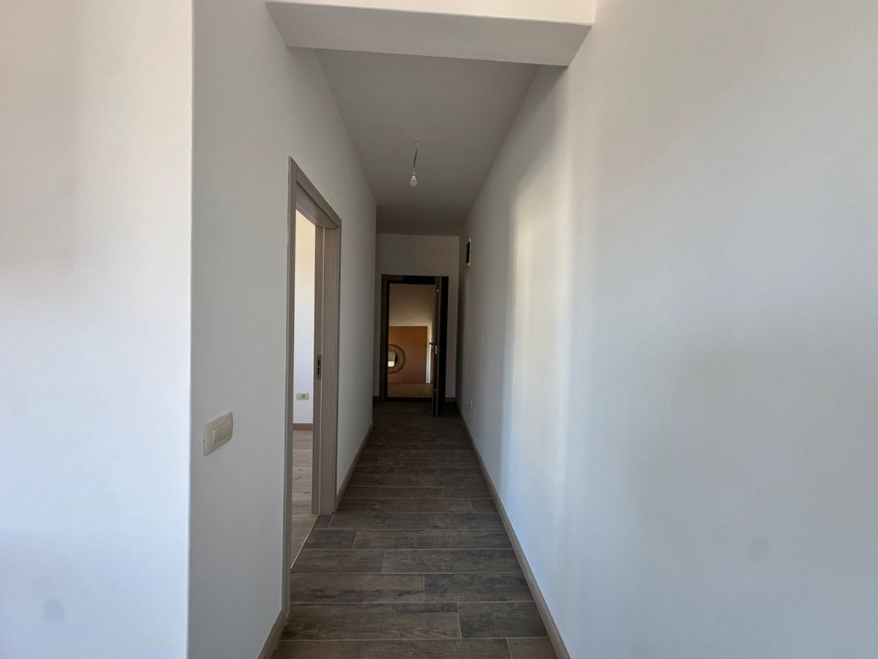 Heller Flur in der Wohnung, Kumbor, Montenegro: weiße Wände, Bodenfliesen in Holzoptik und Innentüren.