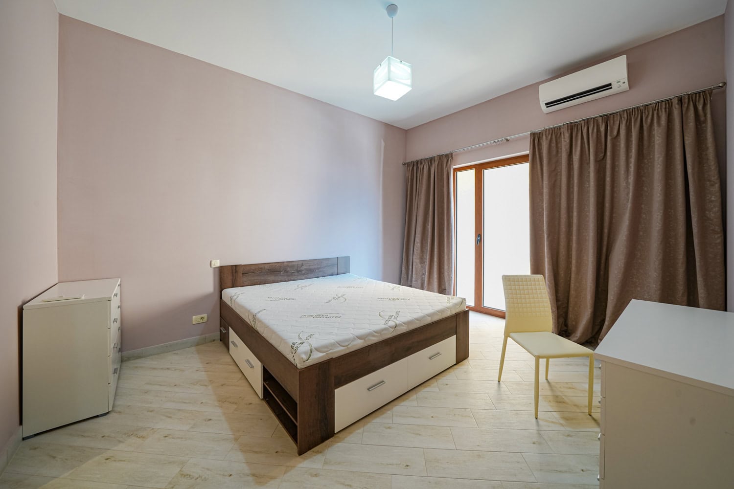 Svetla spavaća soba sa bračnim krevetom i izlazom na balkon u stanu, Bečići, Crna Gora.