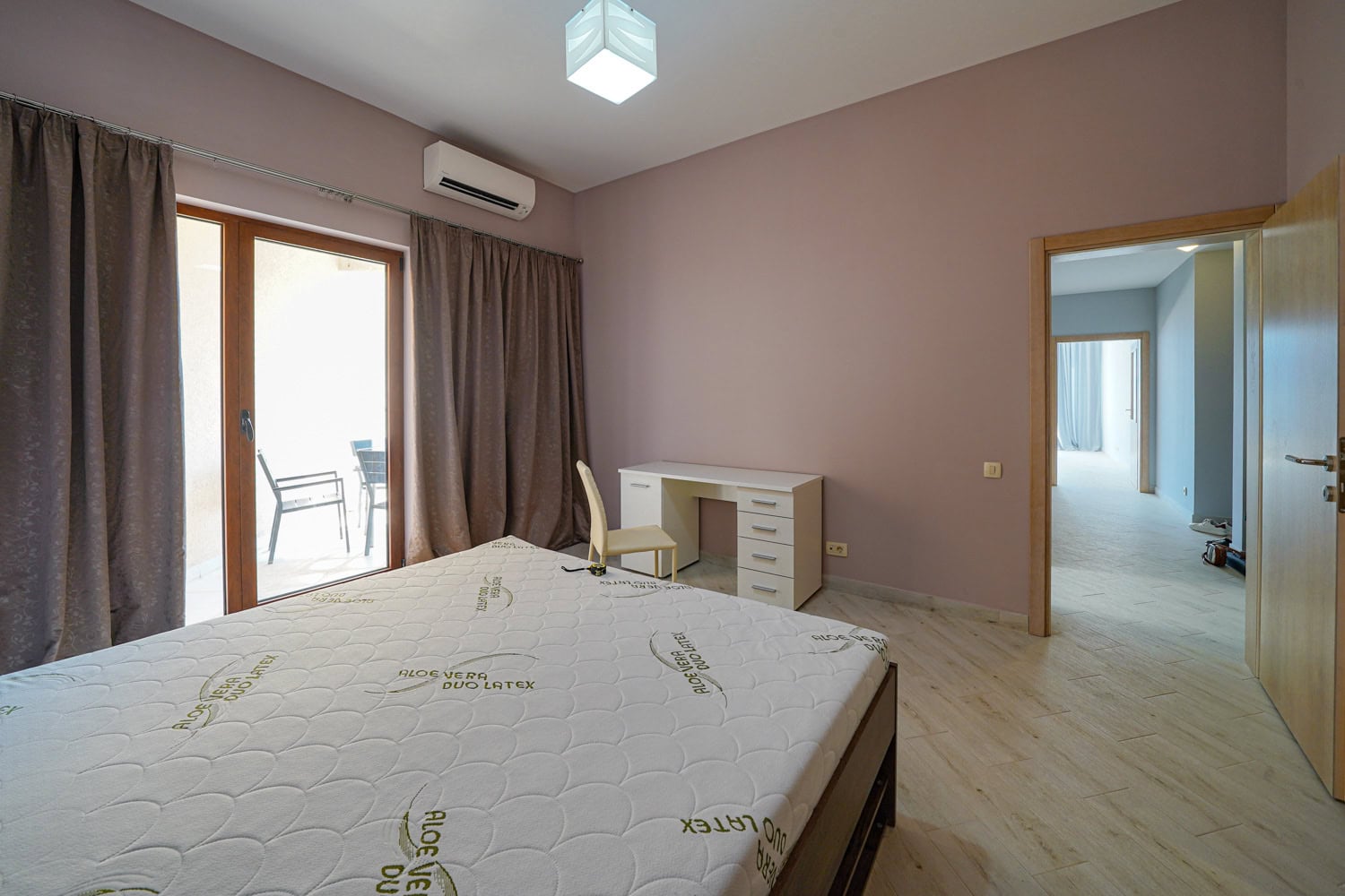 Spavaća soba u stanu u Bečićima, Crna Gora: bračni krevet, radni sto, izlaz na balkon i svetao enterijer.