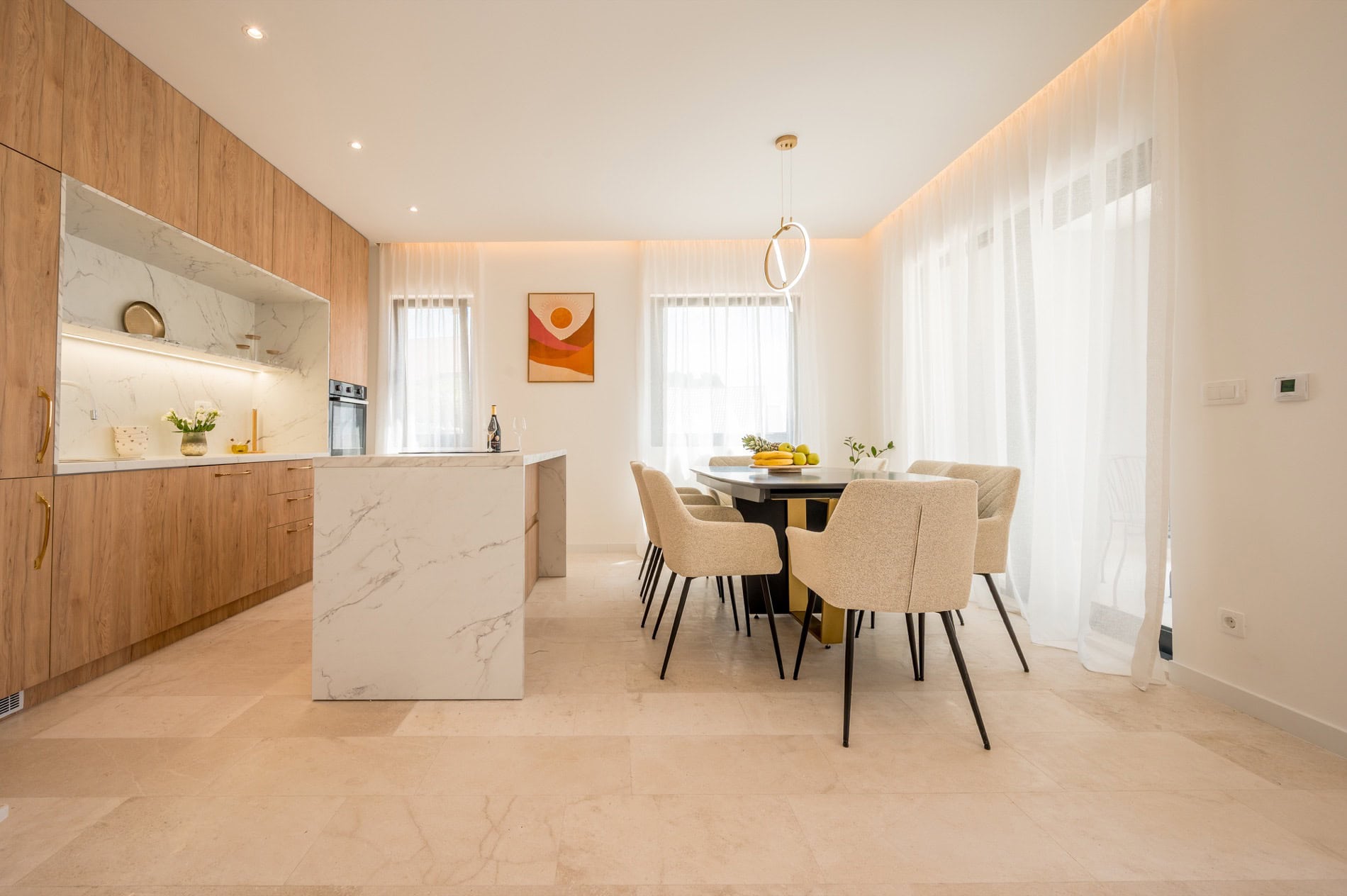 Moderne Wohnküche in einer Villa in Tivat, Montenegro: Marmorinsel, Holzfronten und Essbereich.
