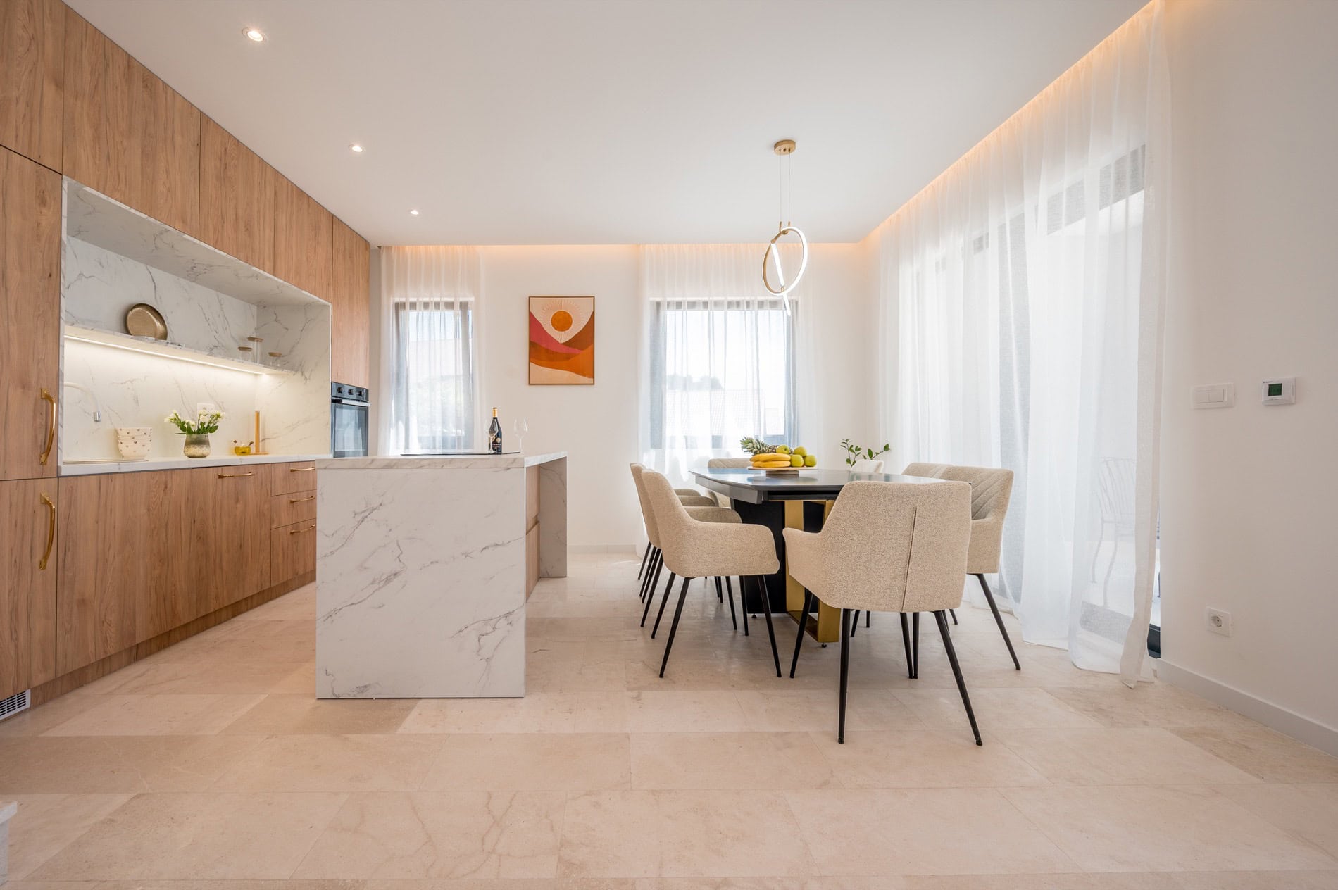 Moderne Wohnküche in einer Villa in Tivat, Montenegro: Marmorinsel, Holzfronten und Essbereich.