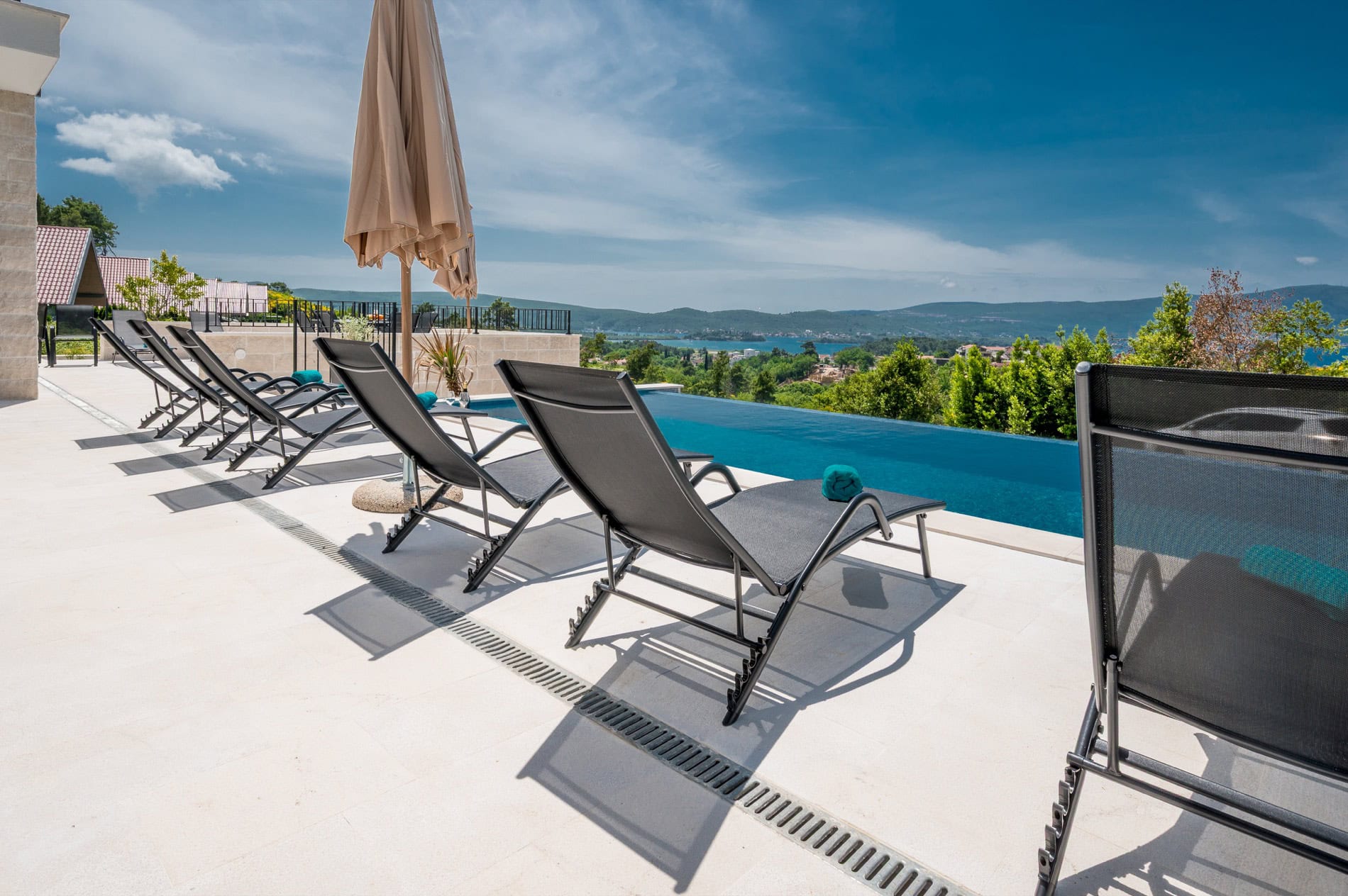 Infinity-Pool mit Liegen und Panoramablick auf das Meer und die Berge an einer Villa in Tivat, Montenegro.