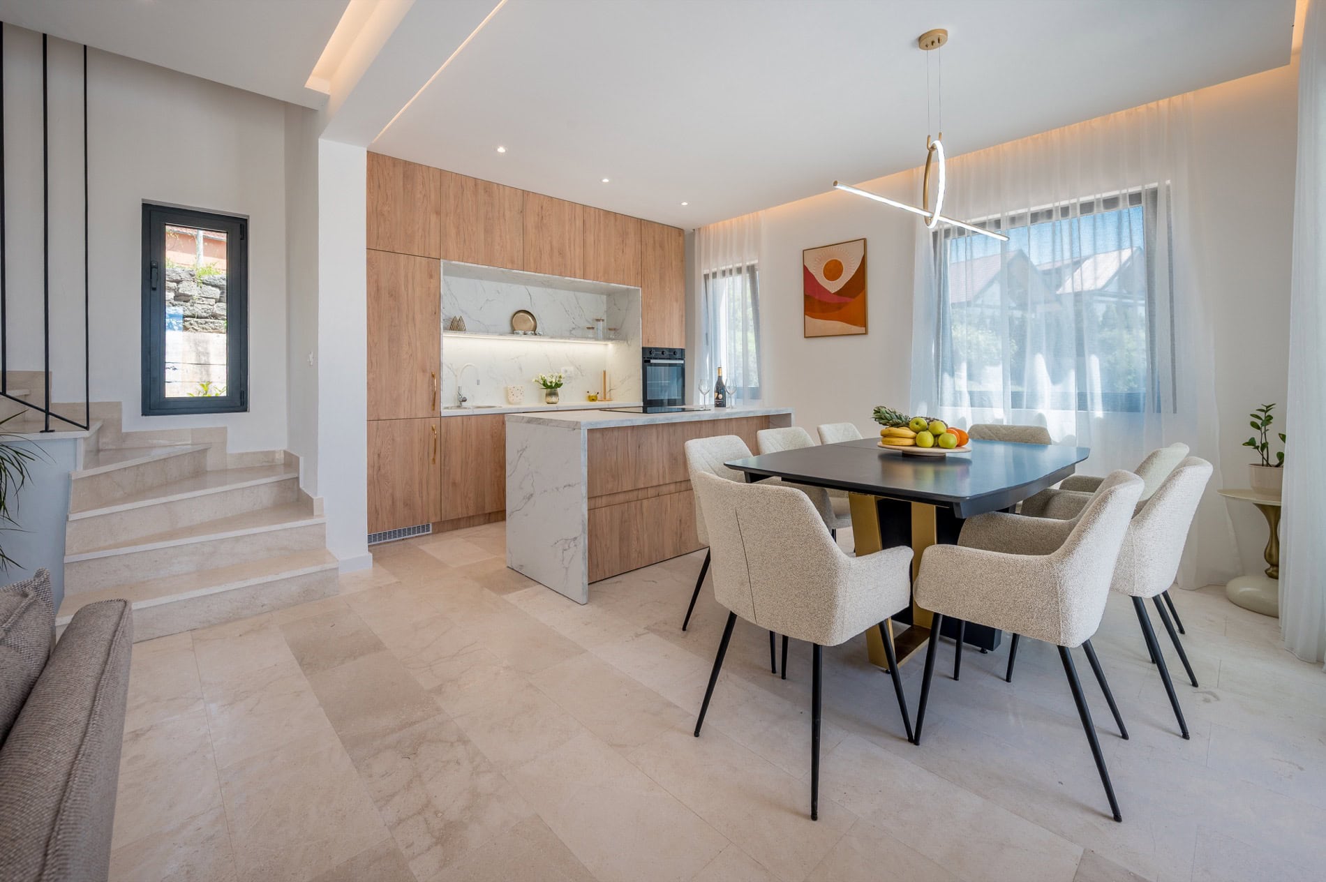 Moderne Wohnküche in einer Villa in Tivat, Montenegro: Marmorkochinsel, Holzfronten und Essbereich.