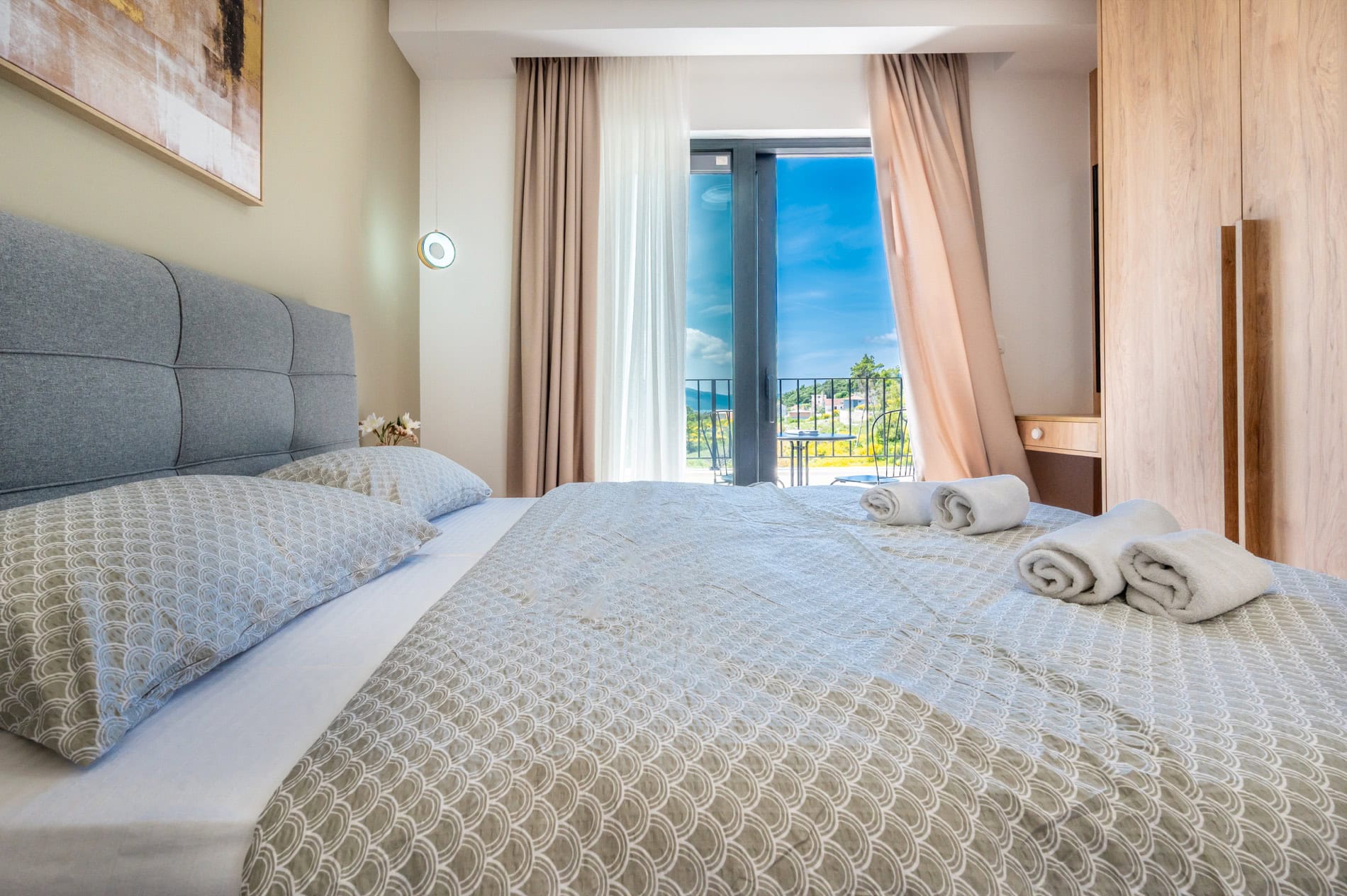 Modernes Schlafzimmer mit Doppelbett und Zugang zum Balkon in der Villa Tivat, Montenegro. Blick auf Berge und Meer.