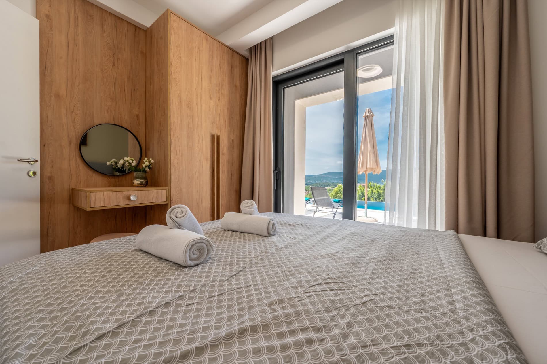 Schlafzimmer in einer Villa in Tivat, Montenegro: Doppelbett, Holzkleiderschrank, Schminktisch und Zugang zum Pool.