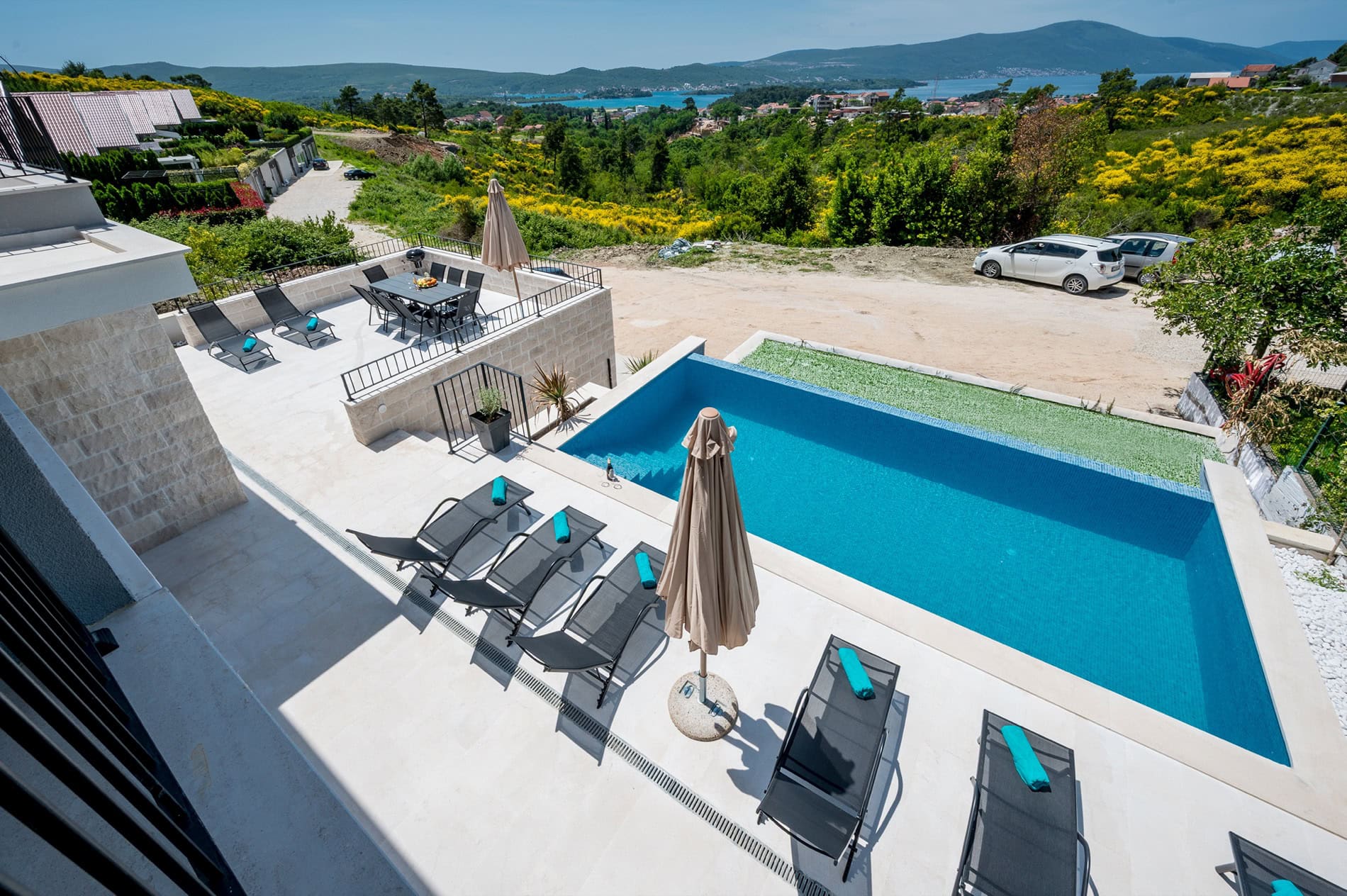 Villa in Tivat, Montenegro: Terrasse mit Pool, Liegen und Essbereich mit Panoramablick auf das Meer und die Berge.