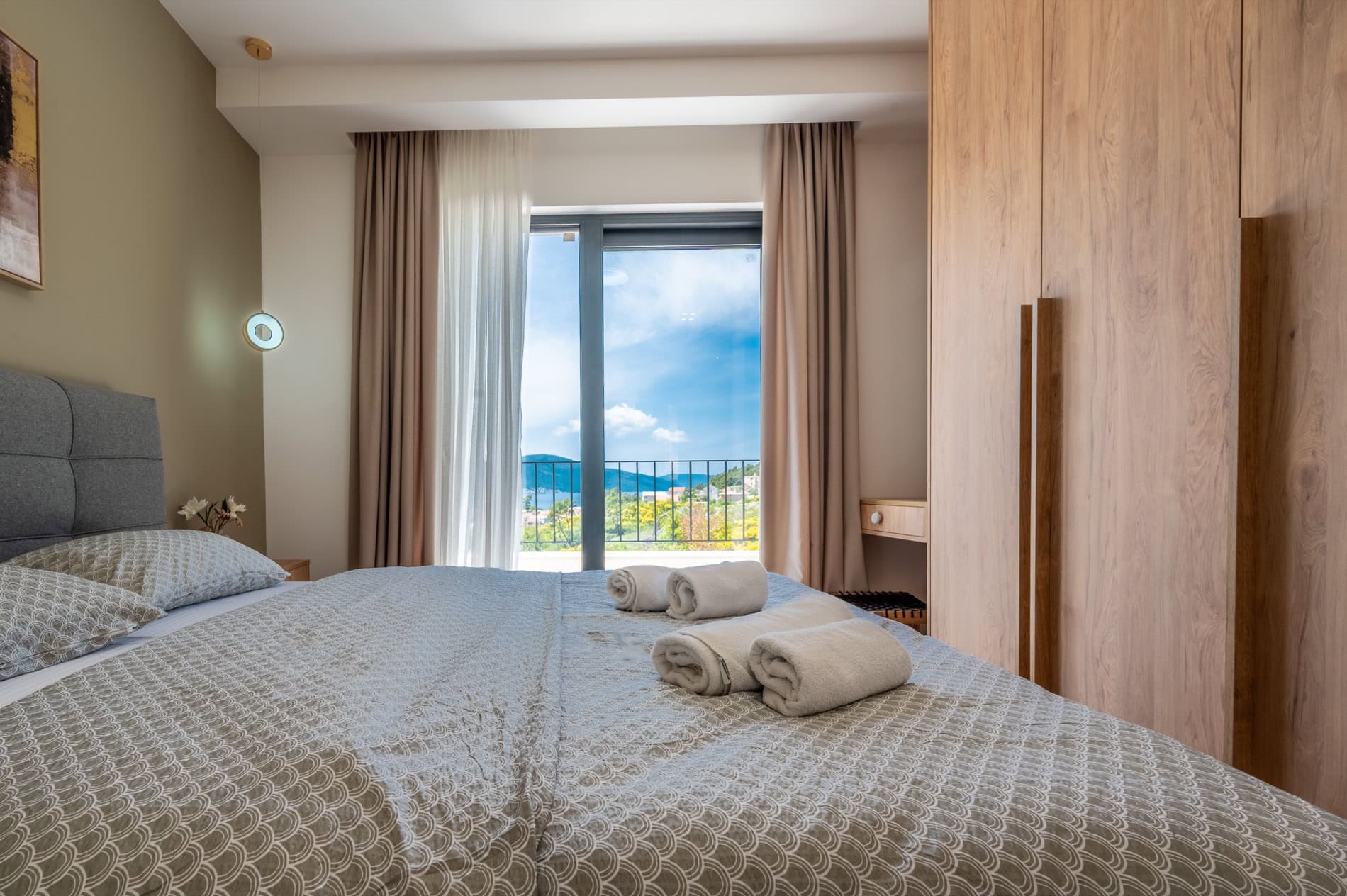 Modernes Schlafzimmer in einer Villa in Tivat, Montenegro: Doppelbett, Holzkleiderschrank und Meerblick vom Balkon.