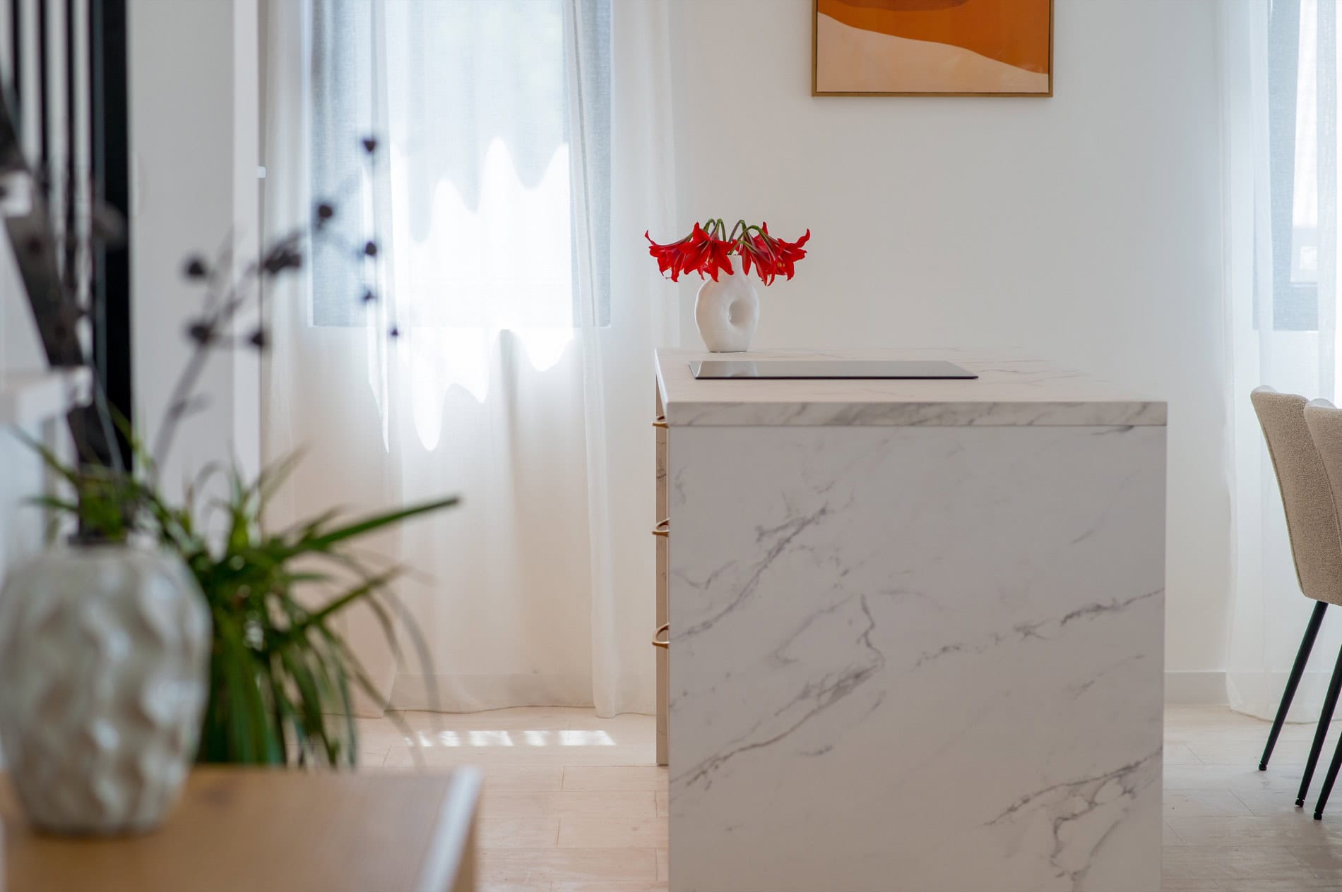 Moderne Küche mit Marmorinsel im Interieur einer Villa in Tivat, Montenegro. Helles Design, Dekor mit Blumen.