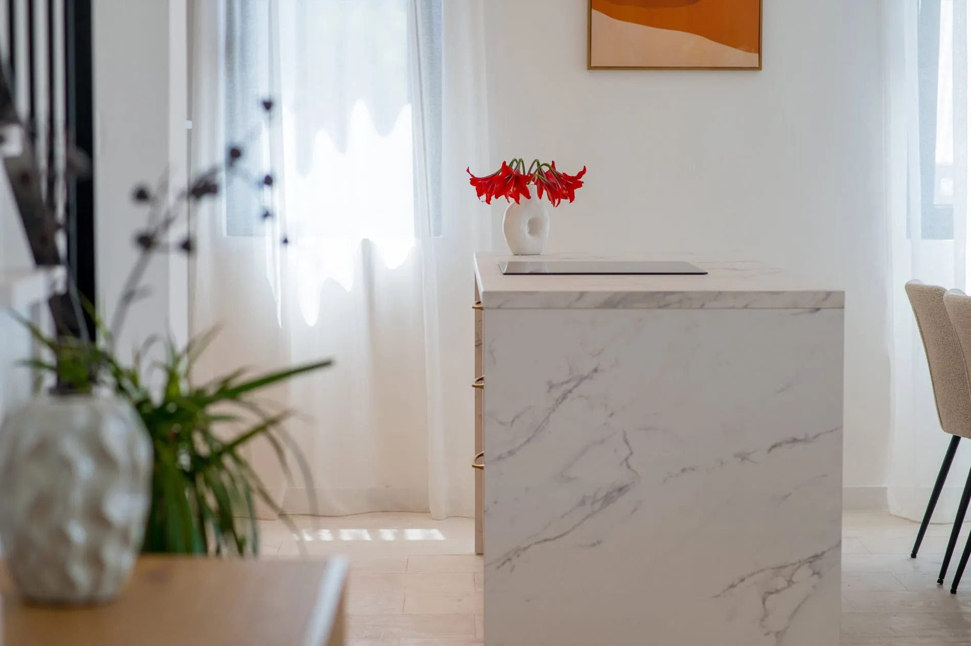 Moderne Küche mit Marmorinsel im Interieur einer Villa in Tivat, Montenegro. Helles Design, Dekor mit Blumen.