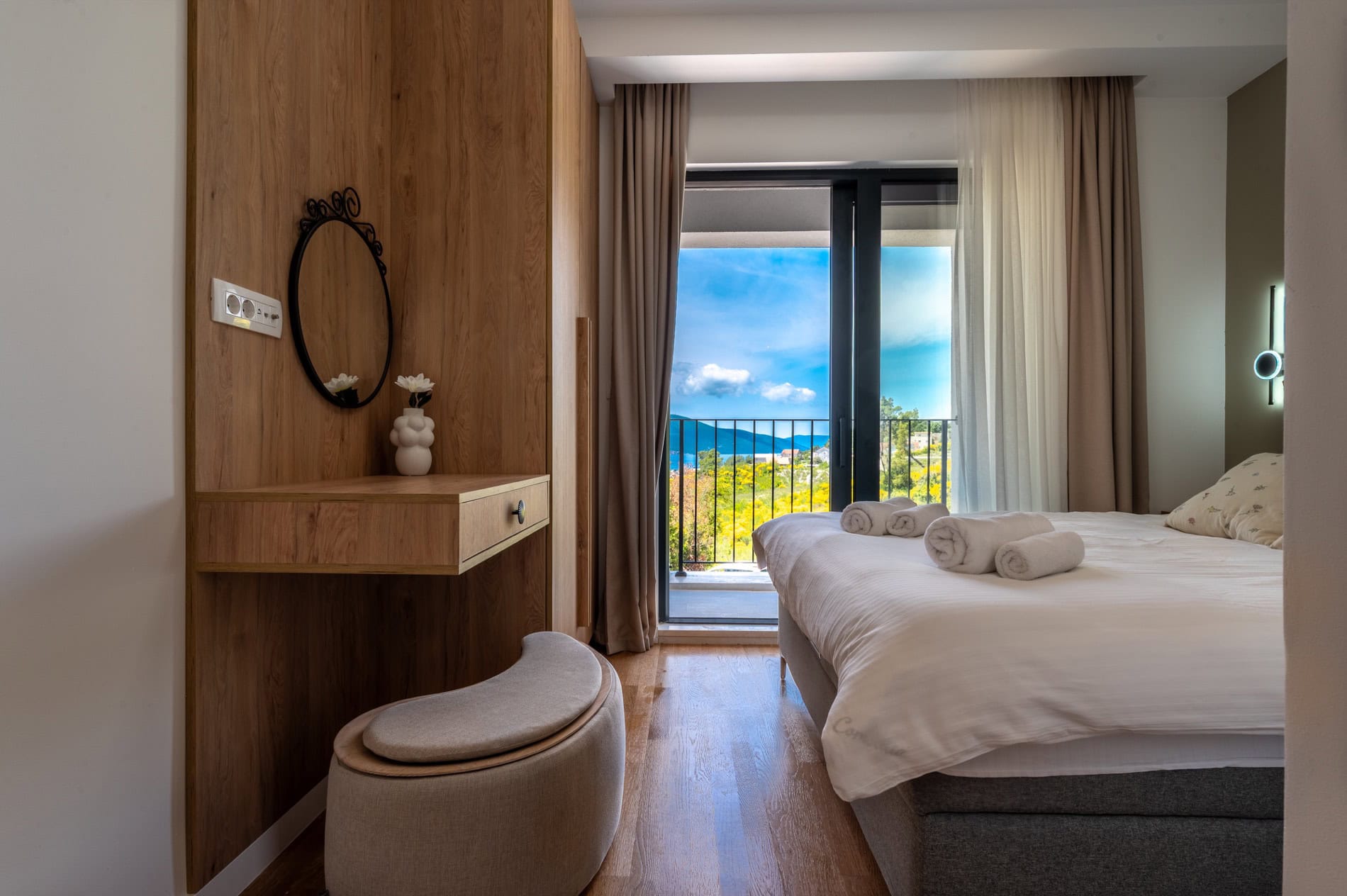 Modernes Schlafzimmer in einer Villa in Tivat, Montenegro: Doppelbett, hölzerner Schminktisch und Meerblick.