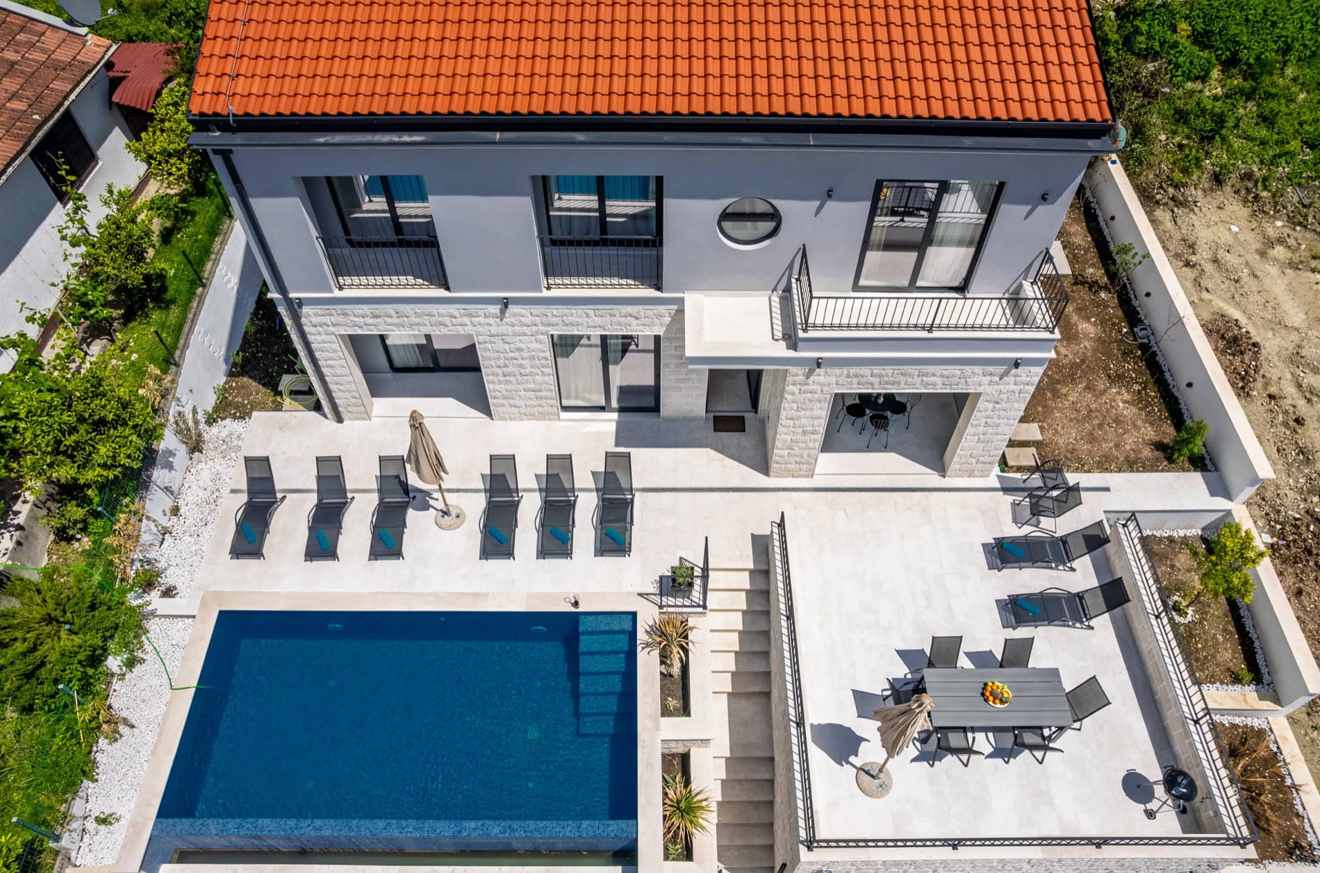 Villa in Tivat, Montenegro: modernes Haus mit Pool, Terrasse, Liegestühlen und Essbereich im Freien.
